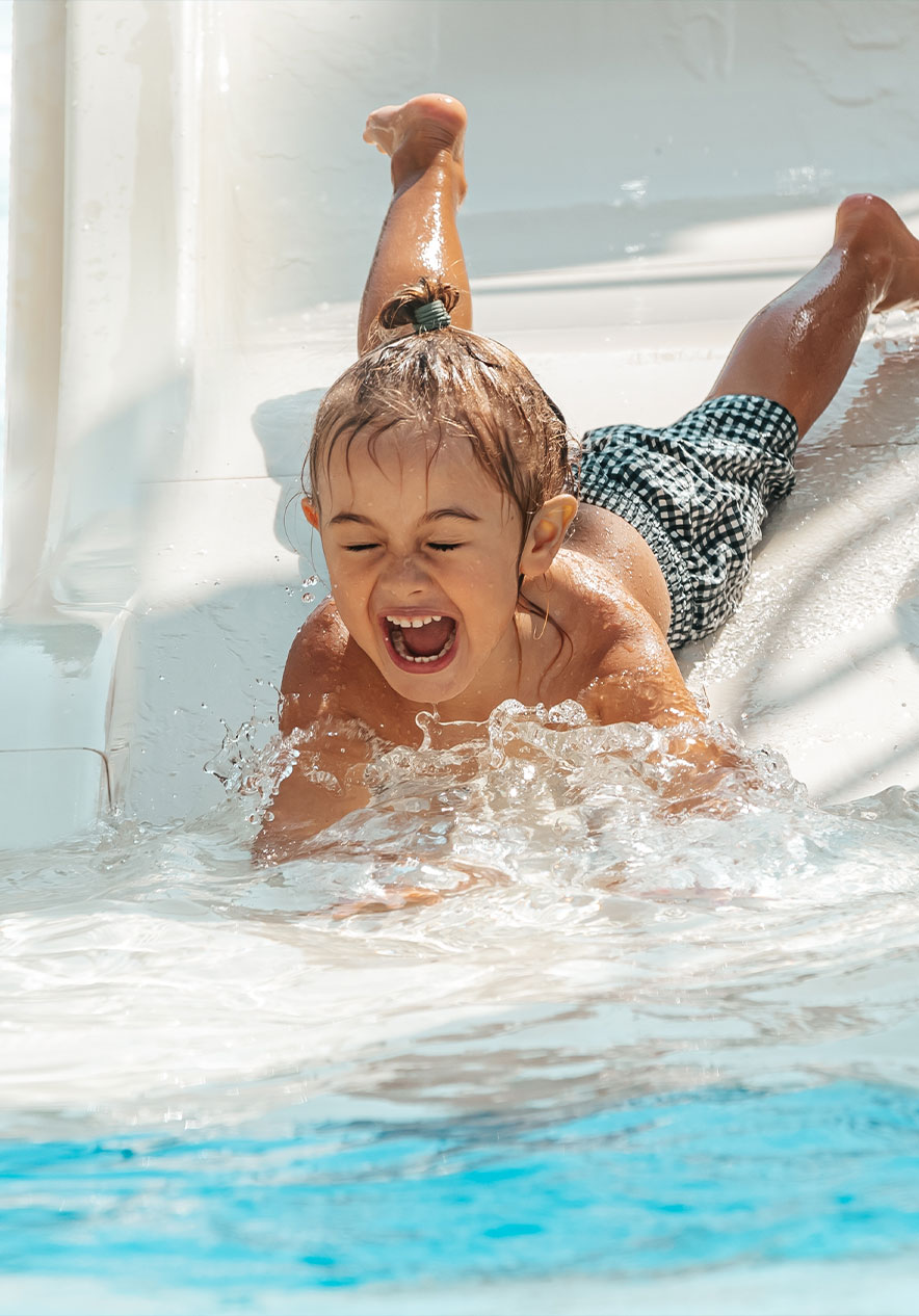 Niña se desliza sonriente por un tobogán de agua en Slide & Splash, Algarve