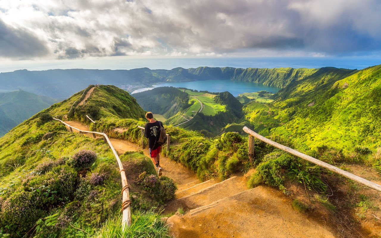 Hombre camina por un sendero de tierra con vista a la Laguna de las Siete Ciudades, Isla de São Miguel, Azores
