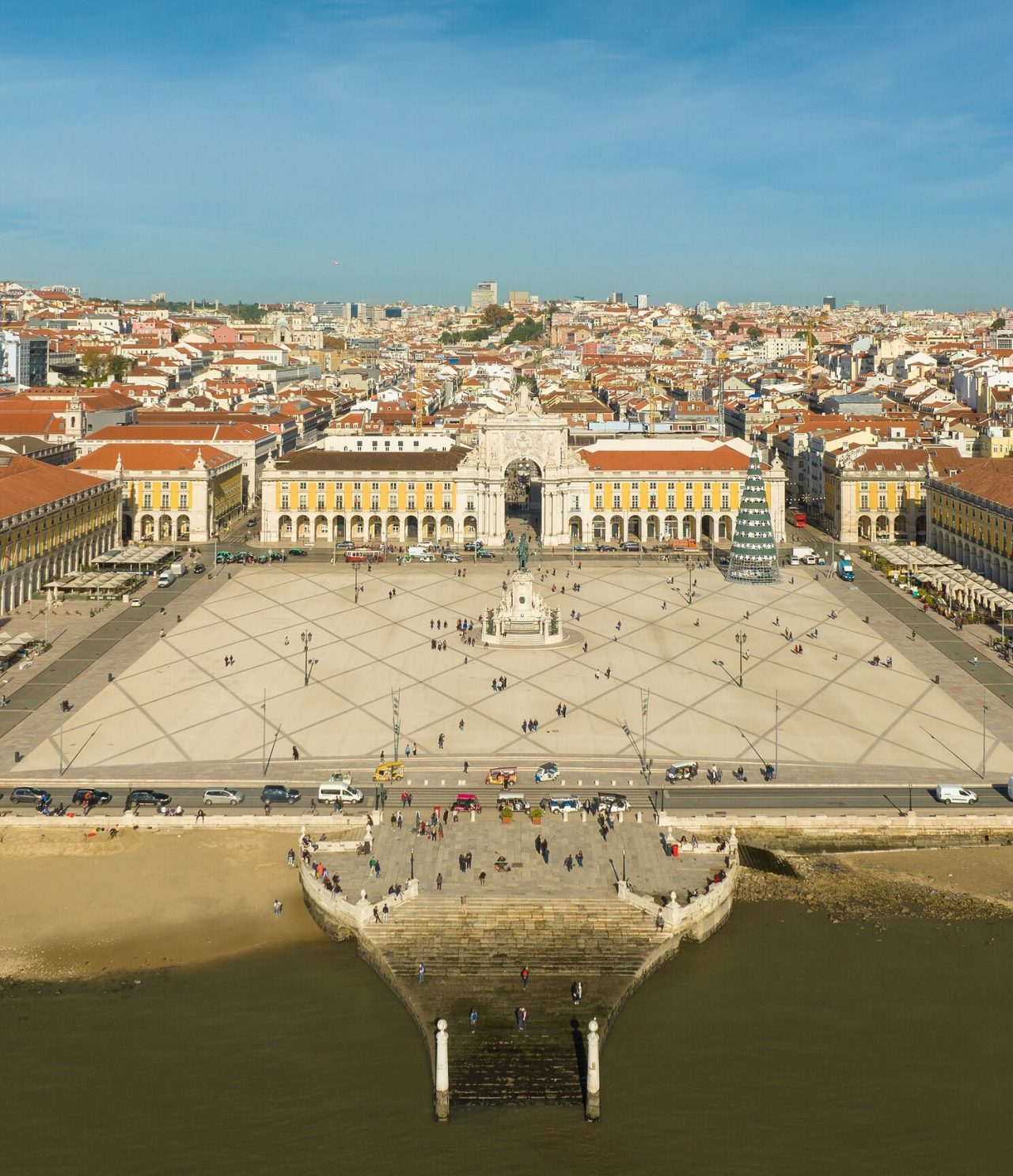Vista aérea de la Praça do Comércio en Lisboa, con el río Tajo al frente, la estatua en el medio y un árbol de Navidad