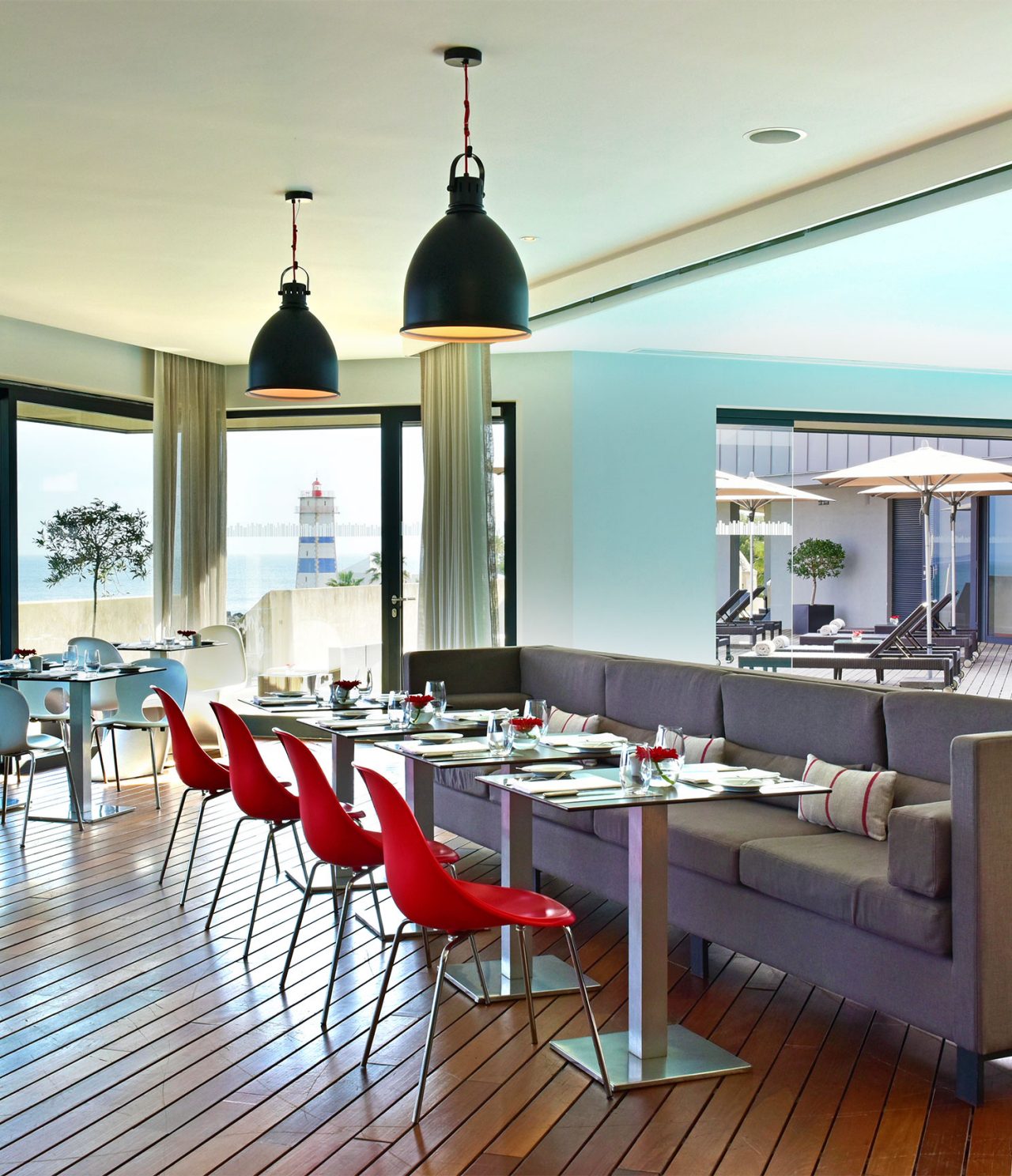 El restaurante Maris Stella, del Hotel 5 Estrellas en Cascais, tiene un sofá gris con mesas y sillas rojas