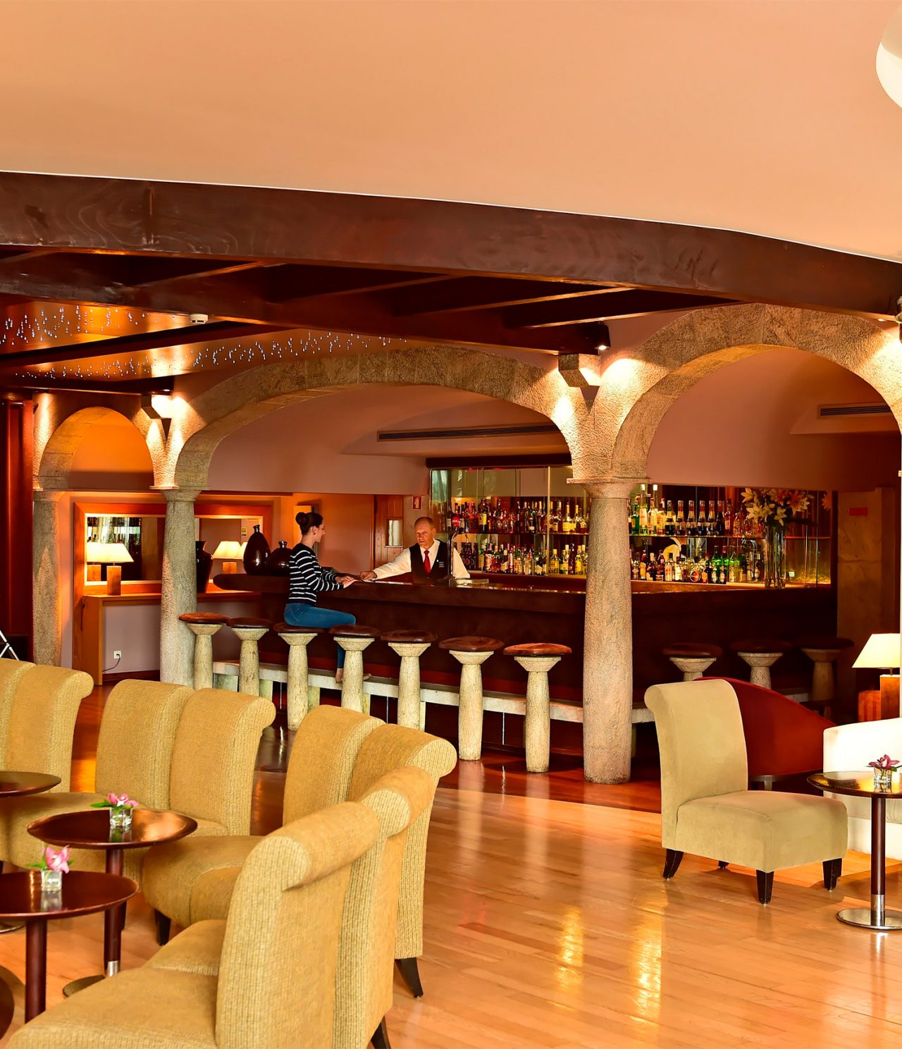 El bar Taverna, del Hotel 5 Estrellas en Madeira, tiene un mostrador con bancos y un empleado sirviendo cócteles