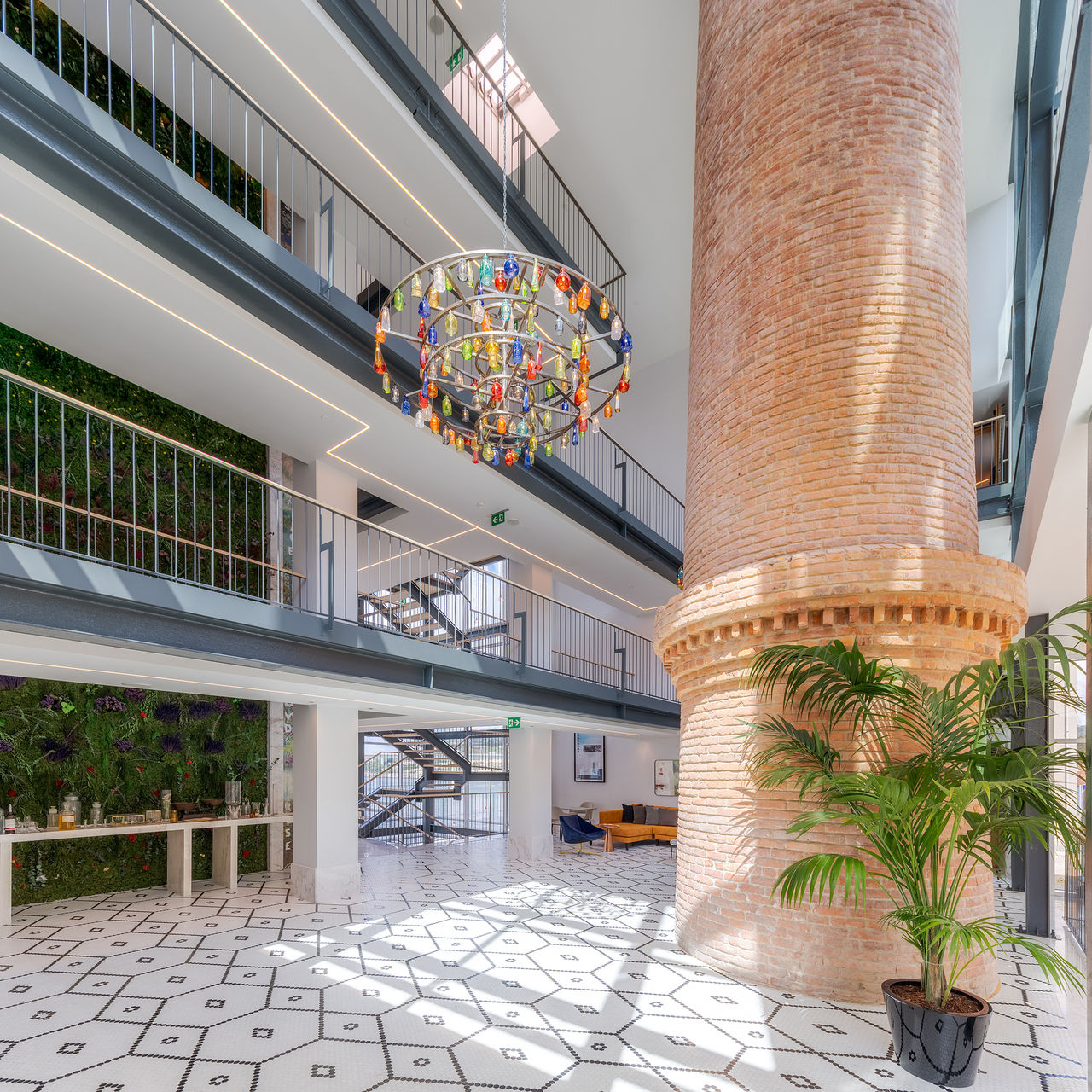 Hall de entrada del Pestana Douro Riverside, con una chimenea de ladrillo y un candelabro de vidrio colorido
