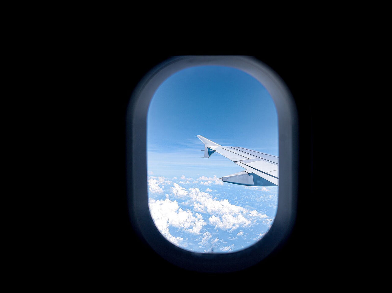 Vista desde la ventana de un avión, el ala, el cielo azul y algunas nubes, hacia Londres