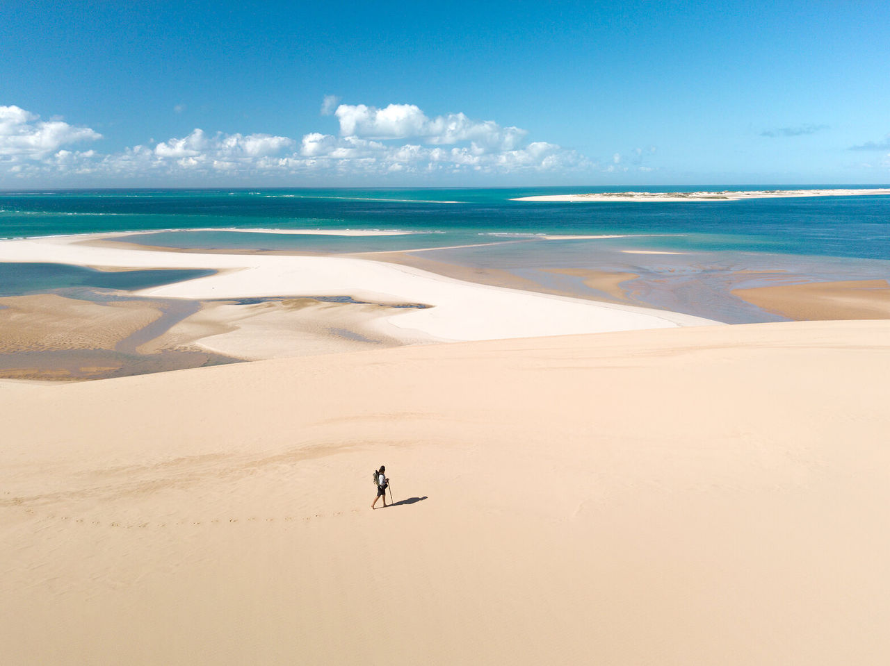 Um caminhante solitário a percorrer as extensas dunas de areia branca de Bazaruto, com o oceano índico no fundo