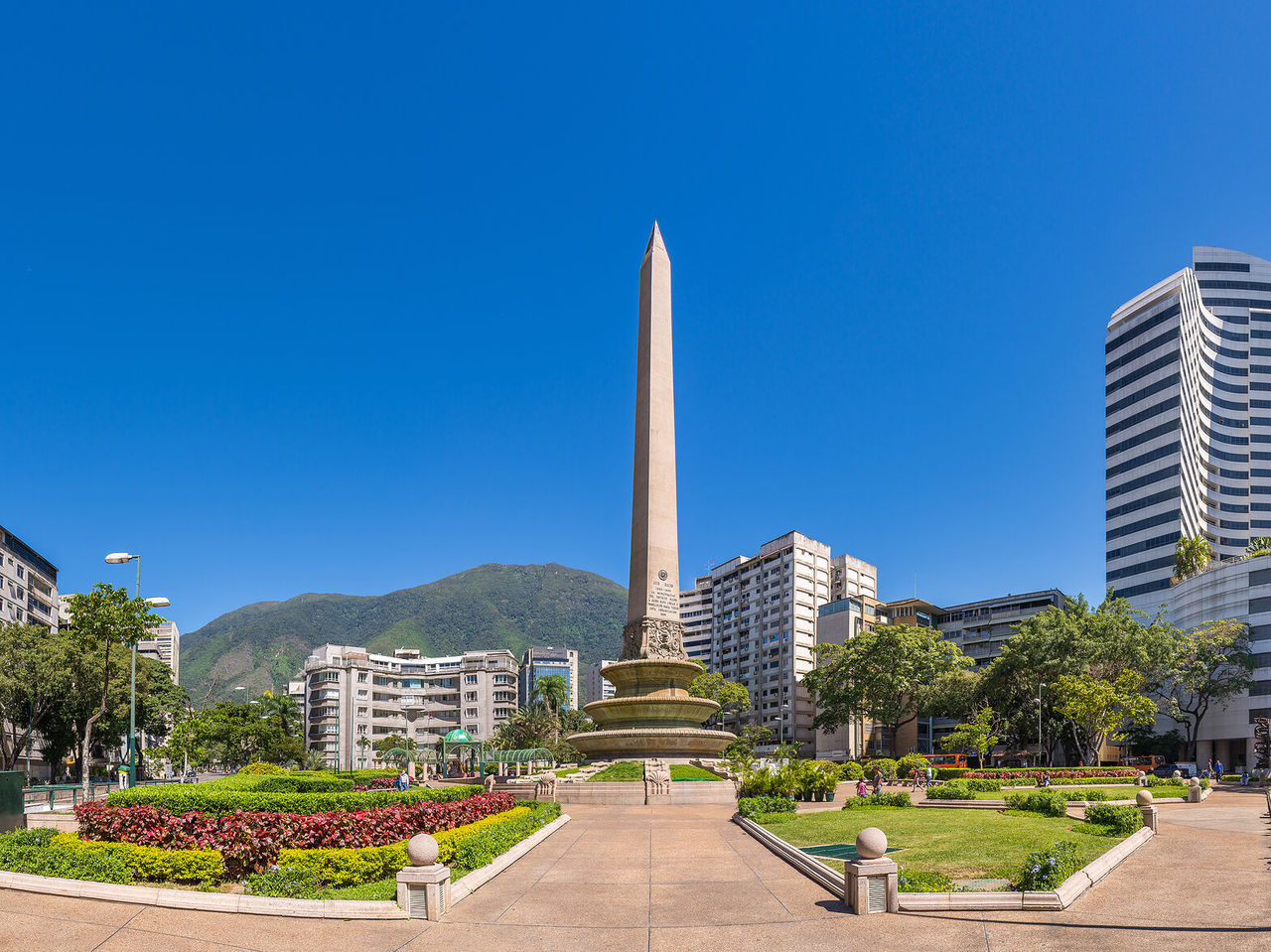 Monumento Obelisco, coluna grande de pedra no meio de um parque com flores, rodeado por edifícios altos em Caracas