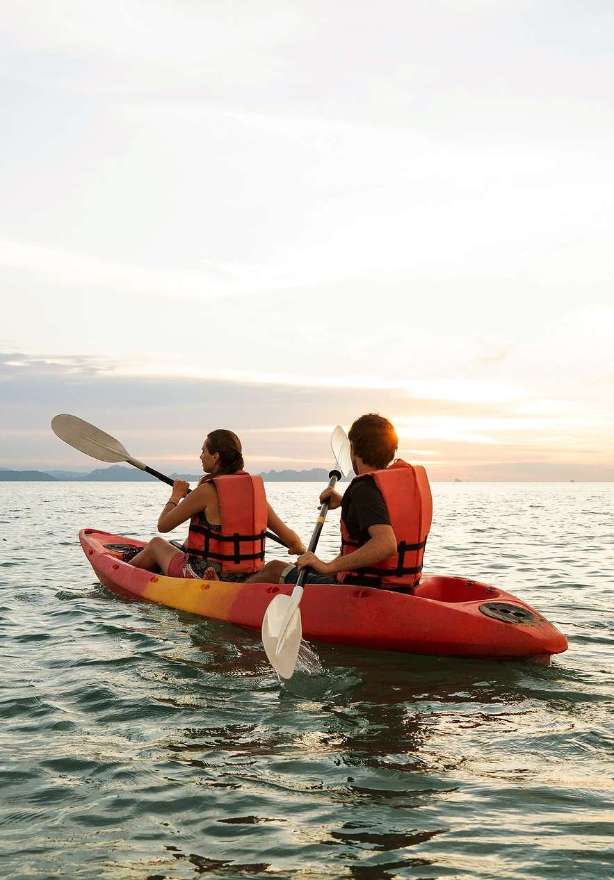 Duas pessoas a remar dentro de um kayak no mar calmo de Tróia