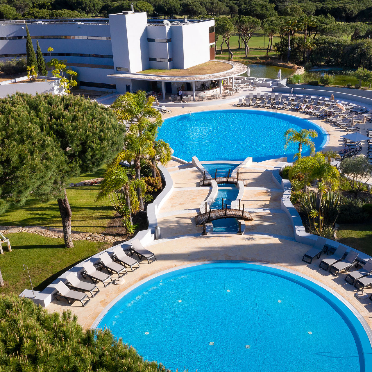 Piscinas exteriores do Pestana Vila Sol, hotel 5 estrelas em Vilamoura, e espreguiçadeiras à sua volta que convidam a relaxar