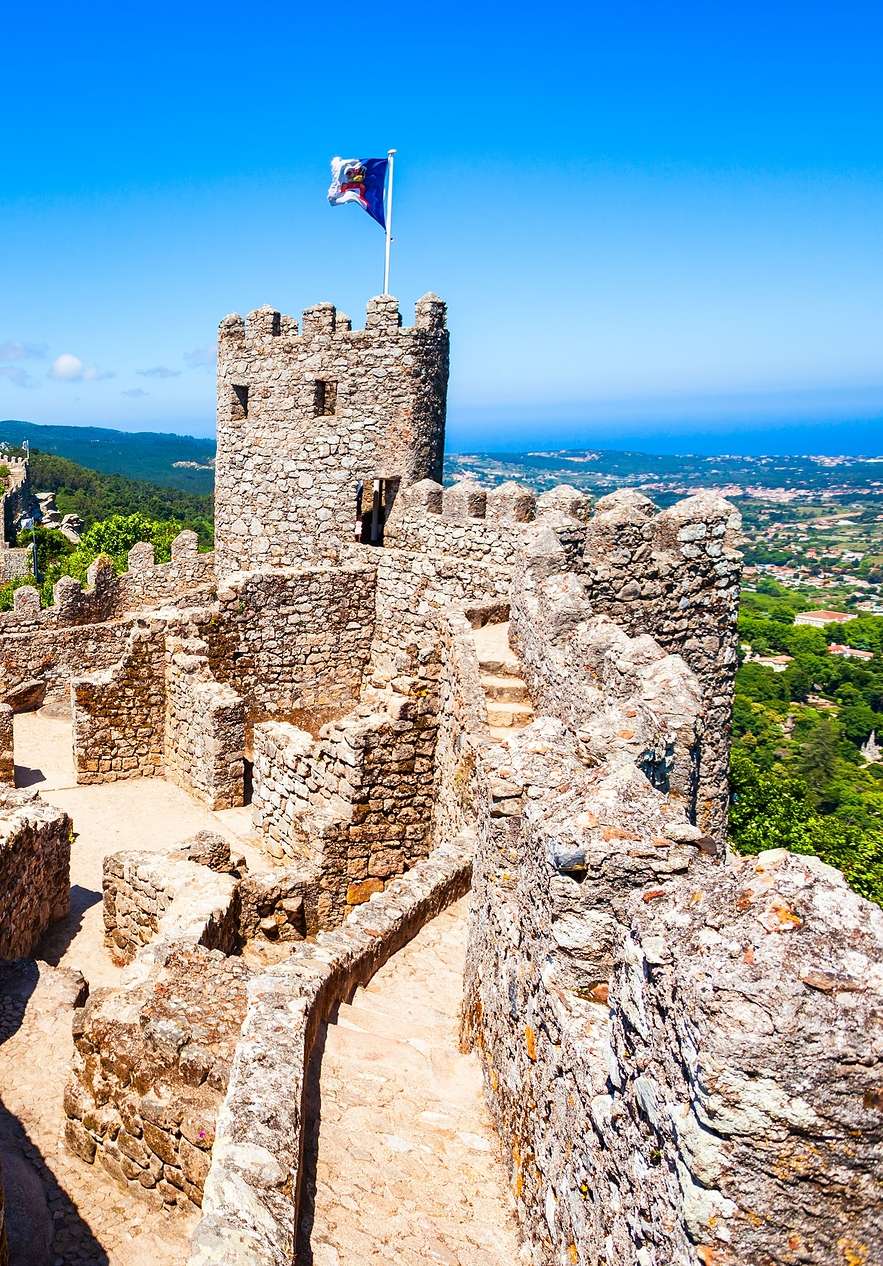 Vista panorâmica do Castelo dos Mouros, em Sintra, com muralhas em pedra, torres e a maravilhosa paisagem circundante