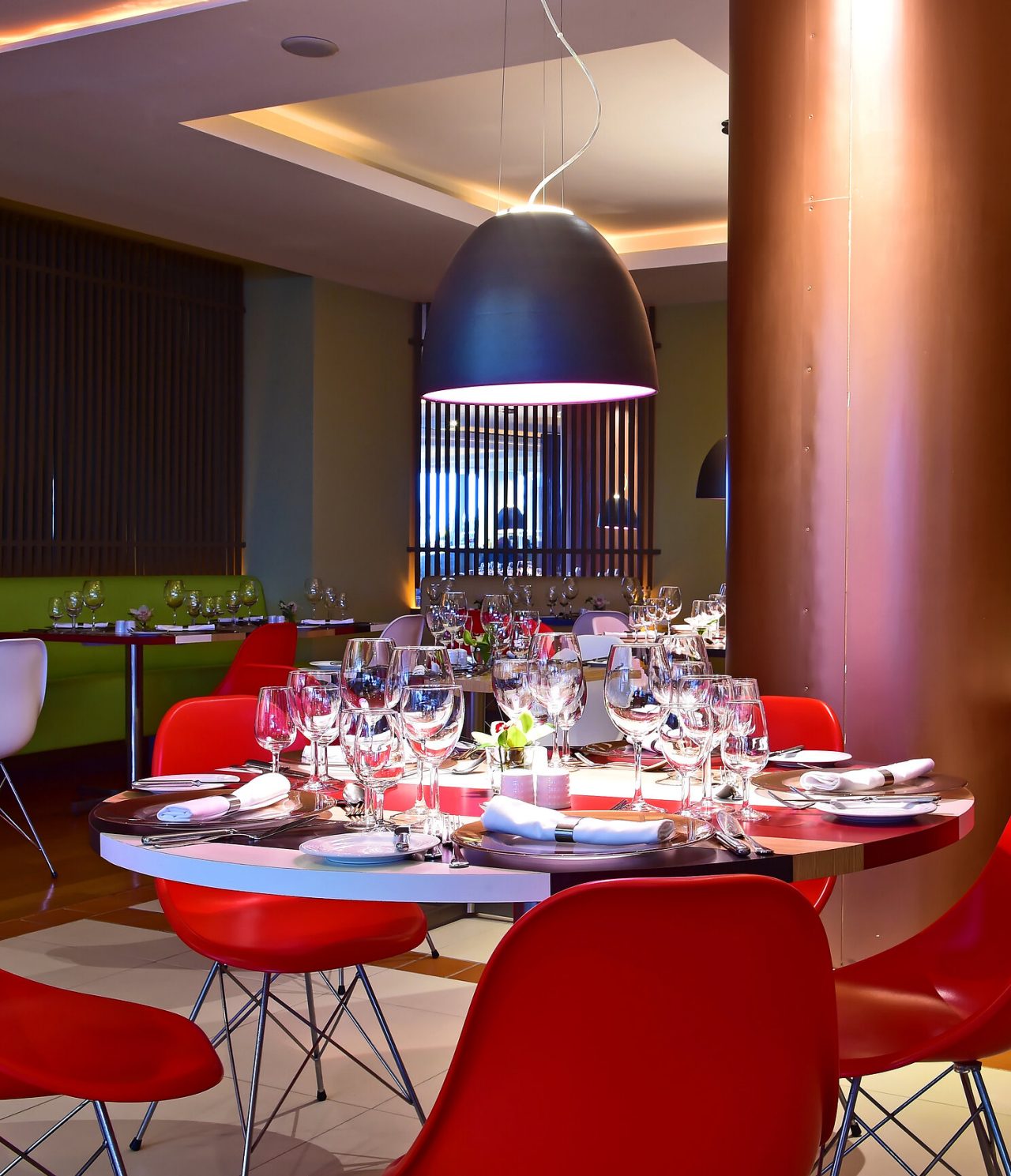 O restaurante Deep Blue, do Hotel 4 Estrelas Junto ao Mar no Funchal, tem uma mesa redonda com cadeiras vermelhas