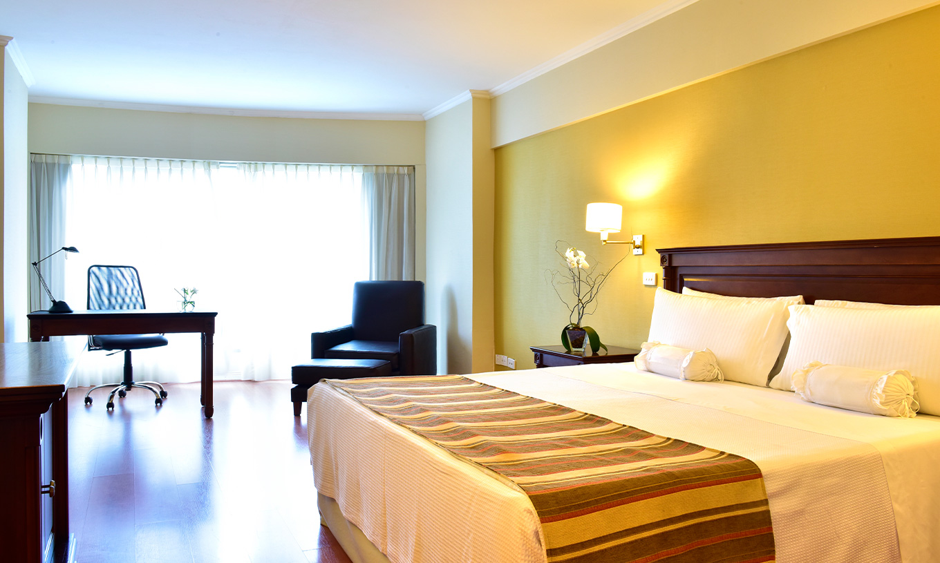 The Queen Standard at Pestana Buenos Aires has a double bed, a bedside table, a desk, and a chair