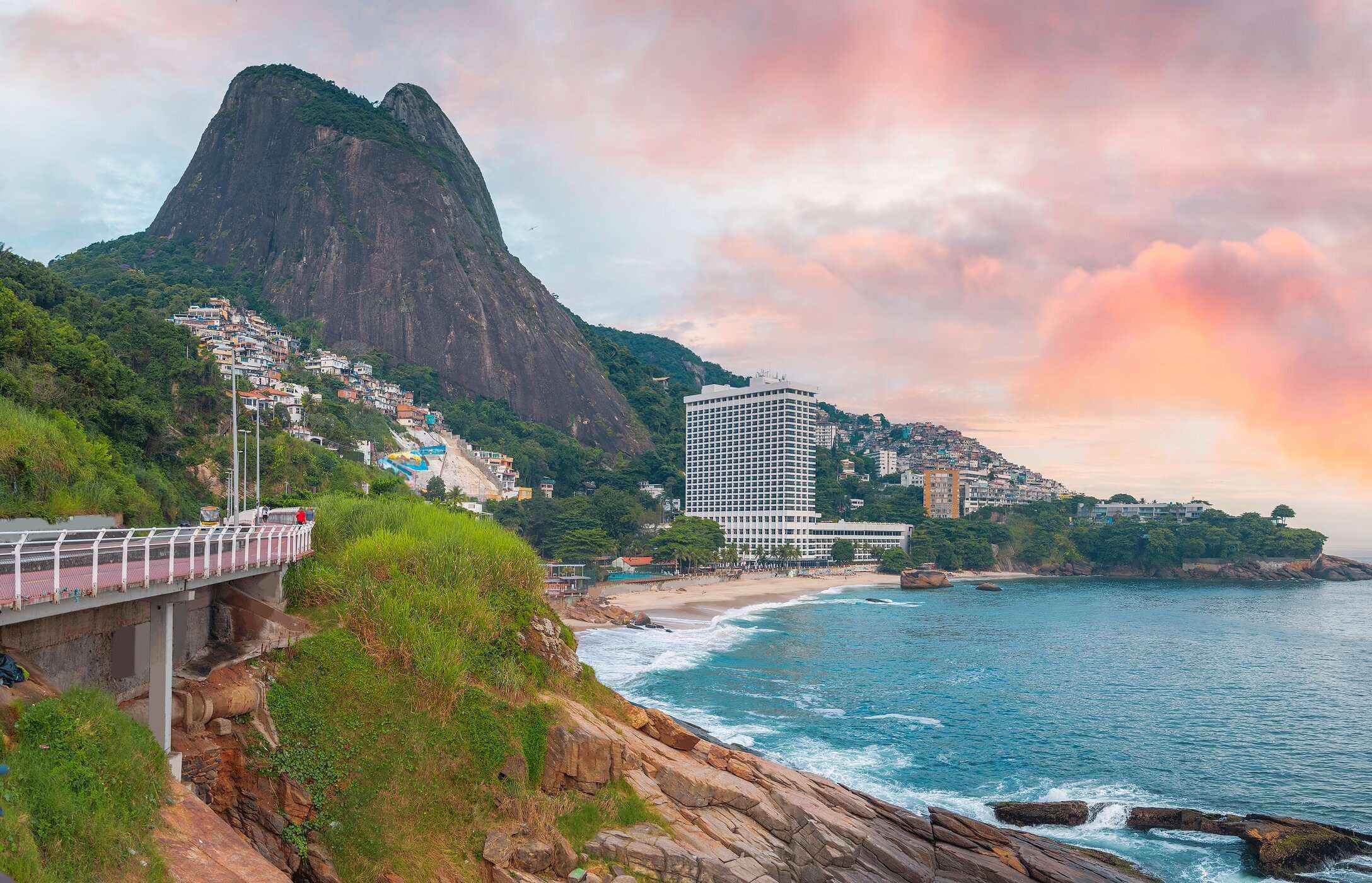 View of Leblon Beach in Rio de Janeiro, Brazil, with a hill in the background and crystal-clear waters at sunset