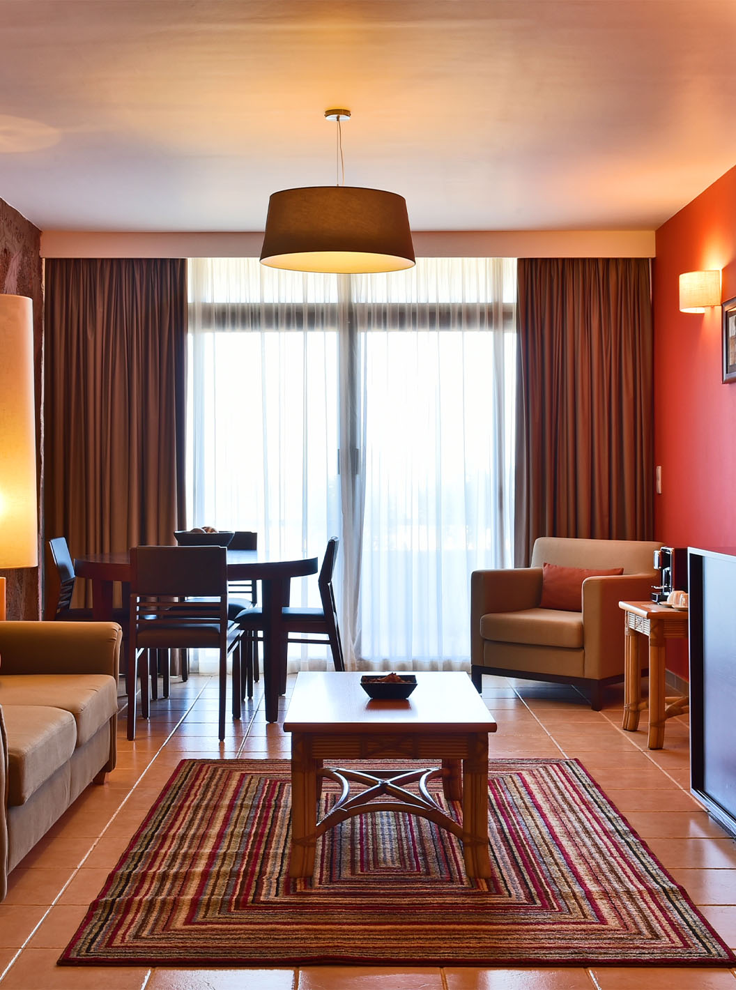 The Premium Suite at Pestana Tropico features a living room with sofa, dining table, armchair, and a coffee table
