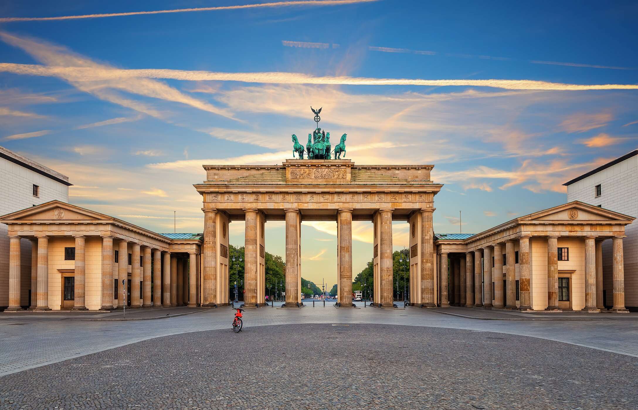 Urban landscape of Berlin, with the iconic Brandenburg Gate, under a blue sky, and Unter den Linden Avenue in the background