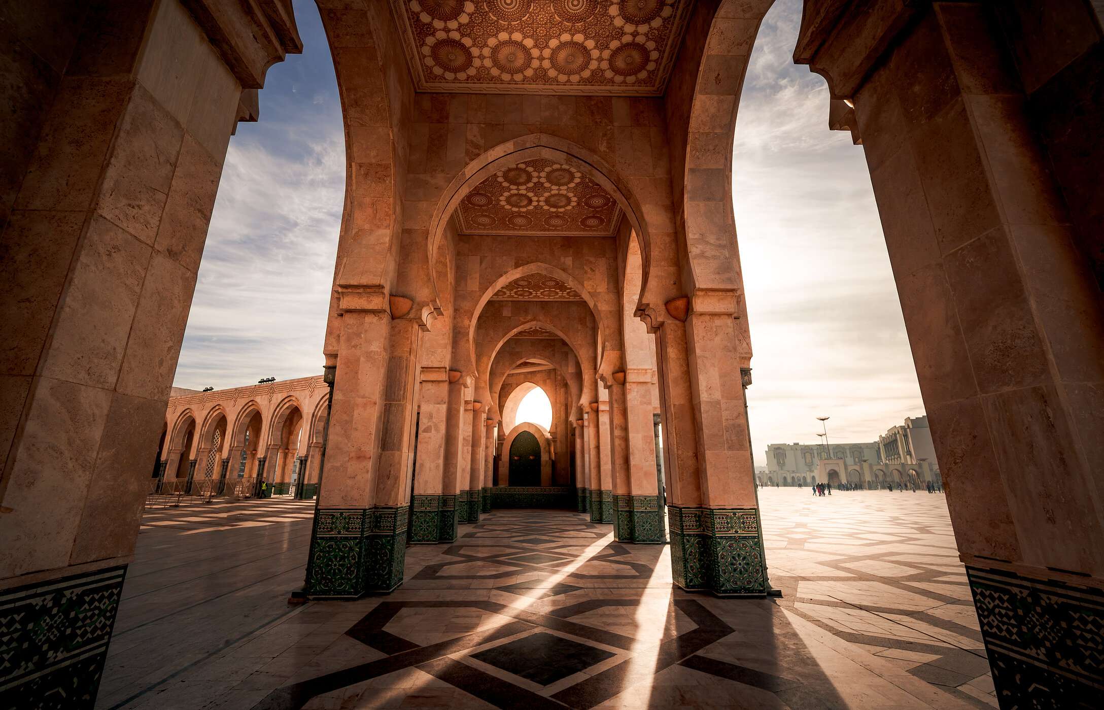 View in the arcades of the Hassan II Mosque in Casablanca, with late afternoon light shining on the architecture