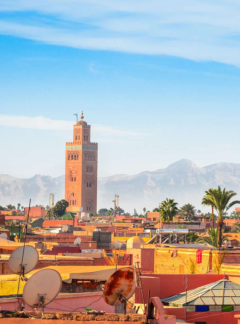 Aerial view of the historic center of Marrakech, with the Koutoubia Mosque tower and the surrounding mountains