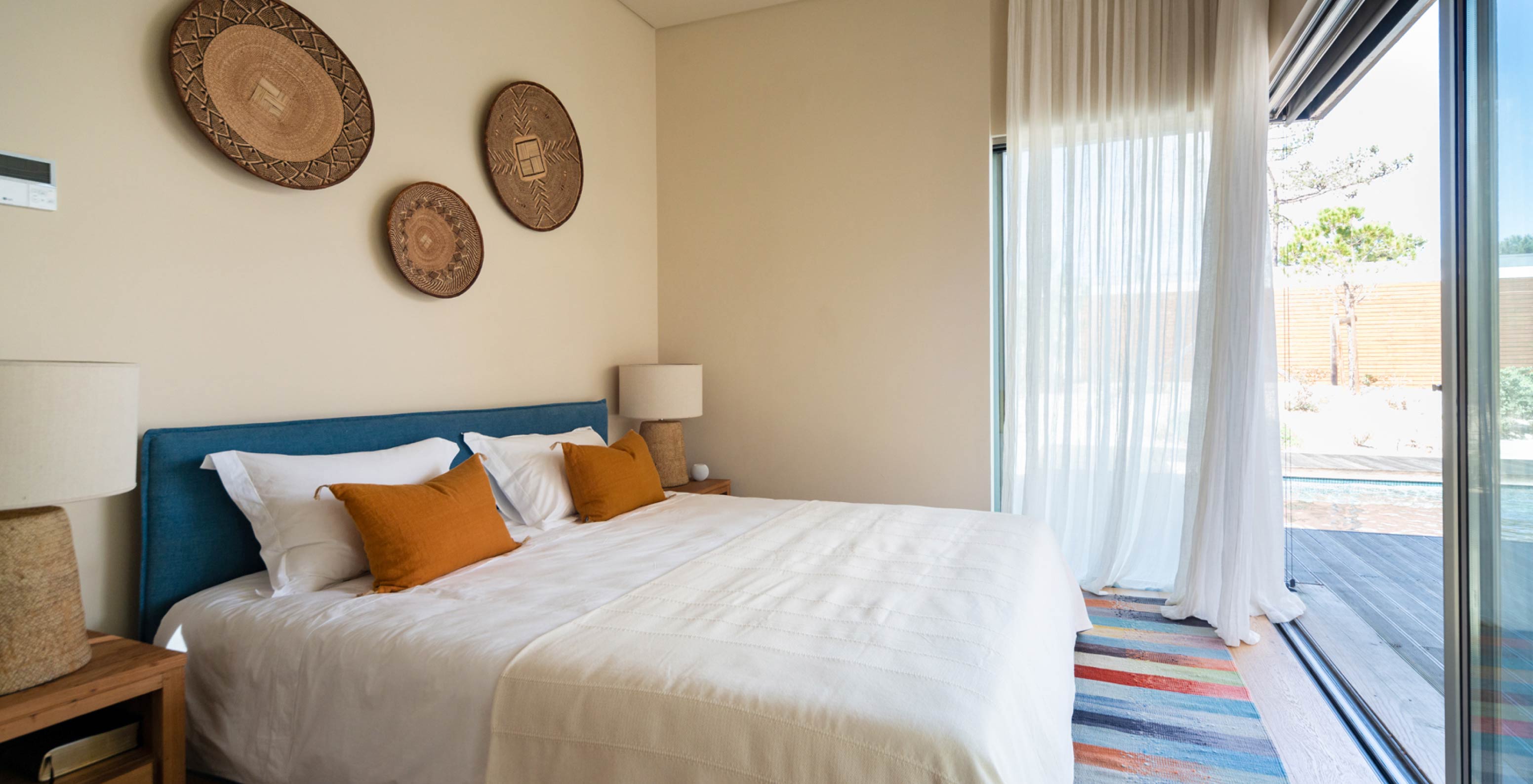 The exclusive villa with a pool at Pestana Tróia Eco Resort has a double bed with orange cushions in front of a window