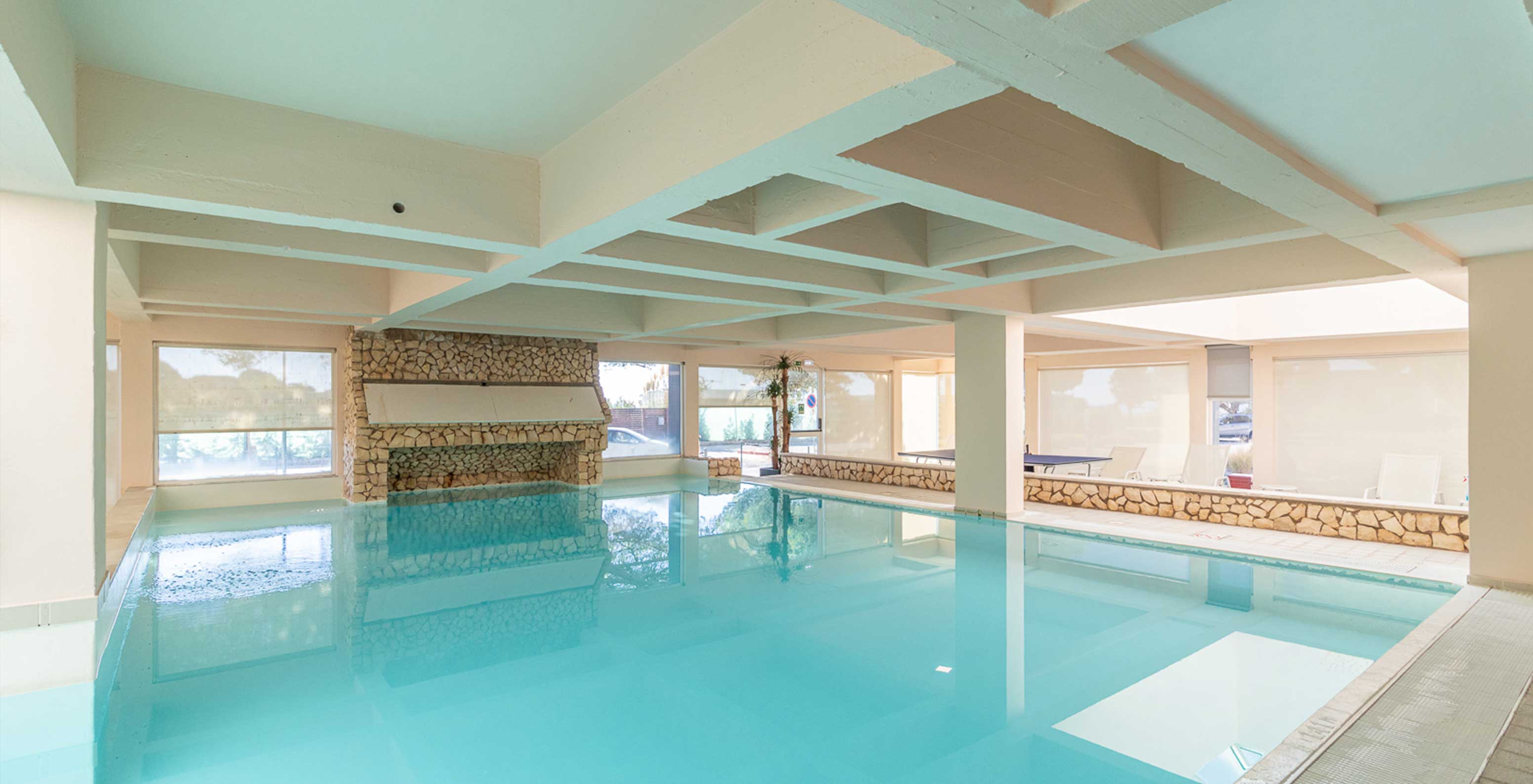 Indoor pool with natural light and speakers in the seafront aparthotel