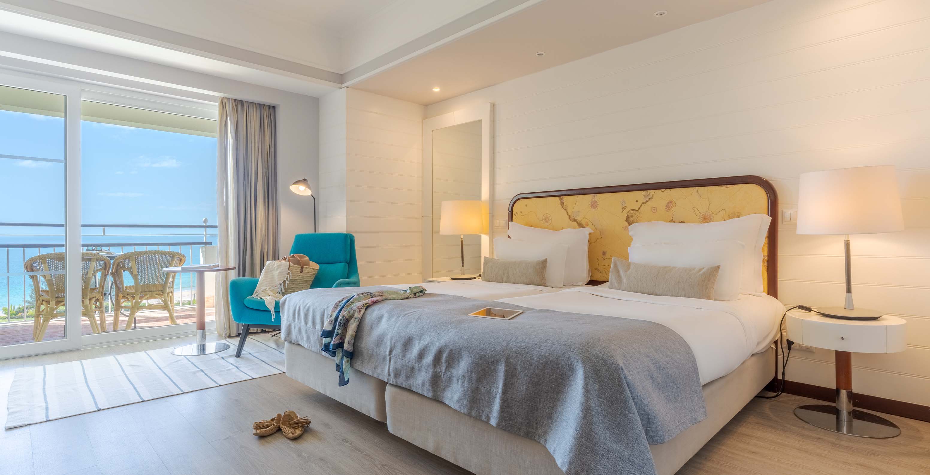 The Sea View Deluxe at Pestana Alvor Praia has two joined beds with a blue armchair and a balcony view