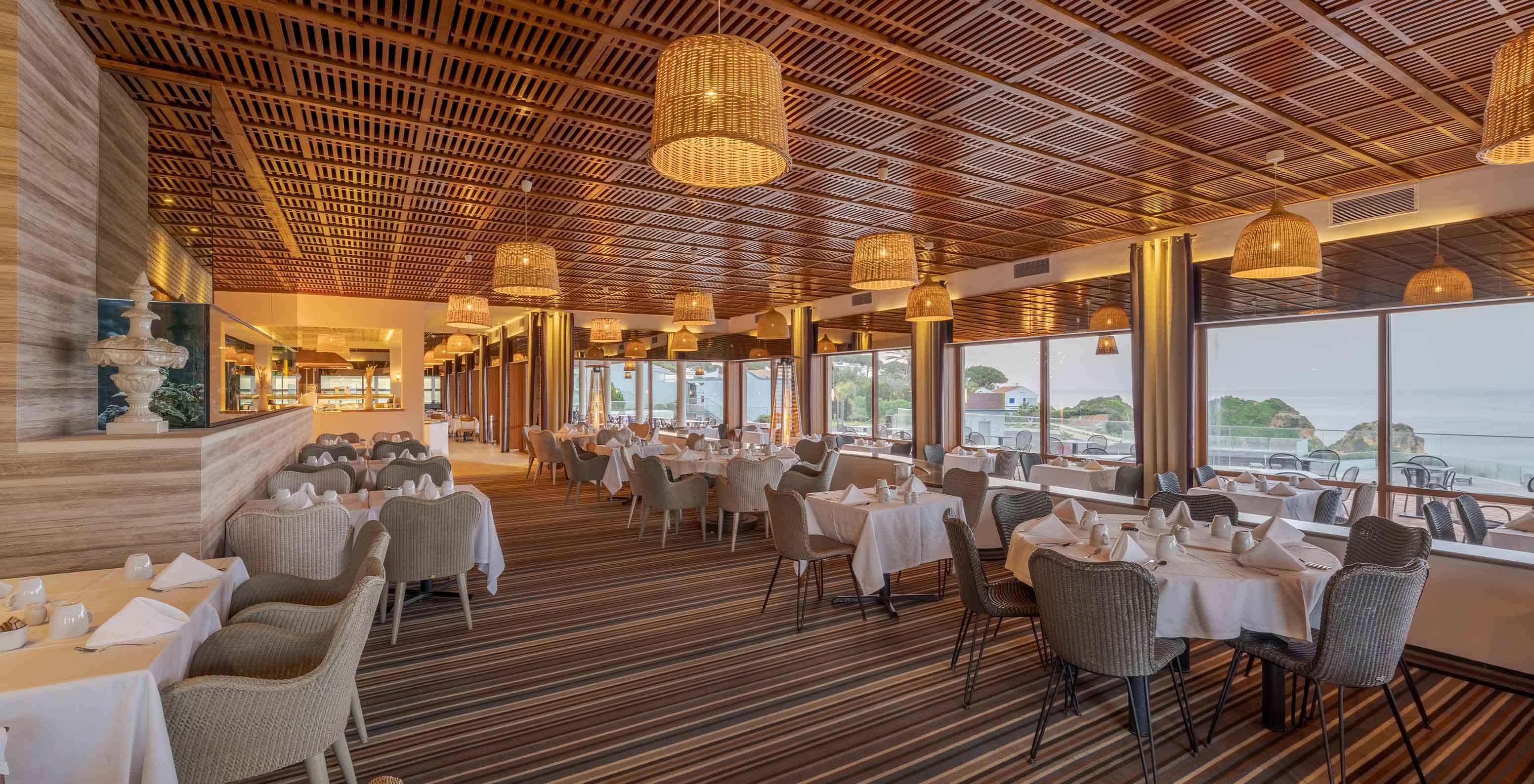 The Almofariz restaurant has wooden slats on the ceiling, an aquarium, and sea views