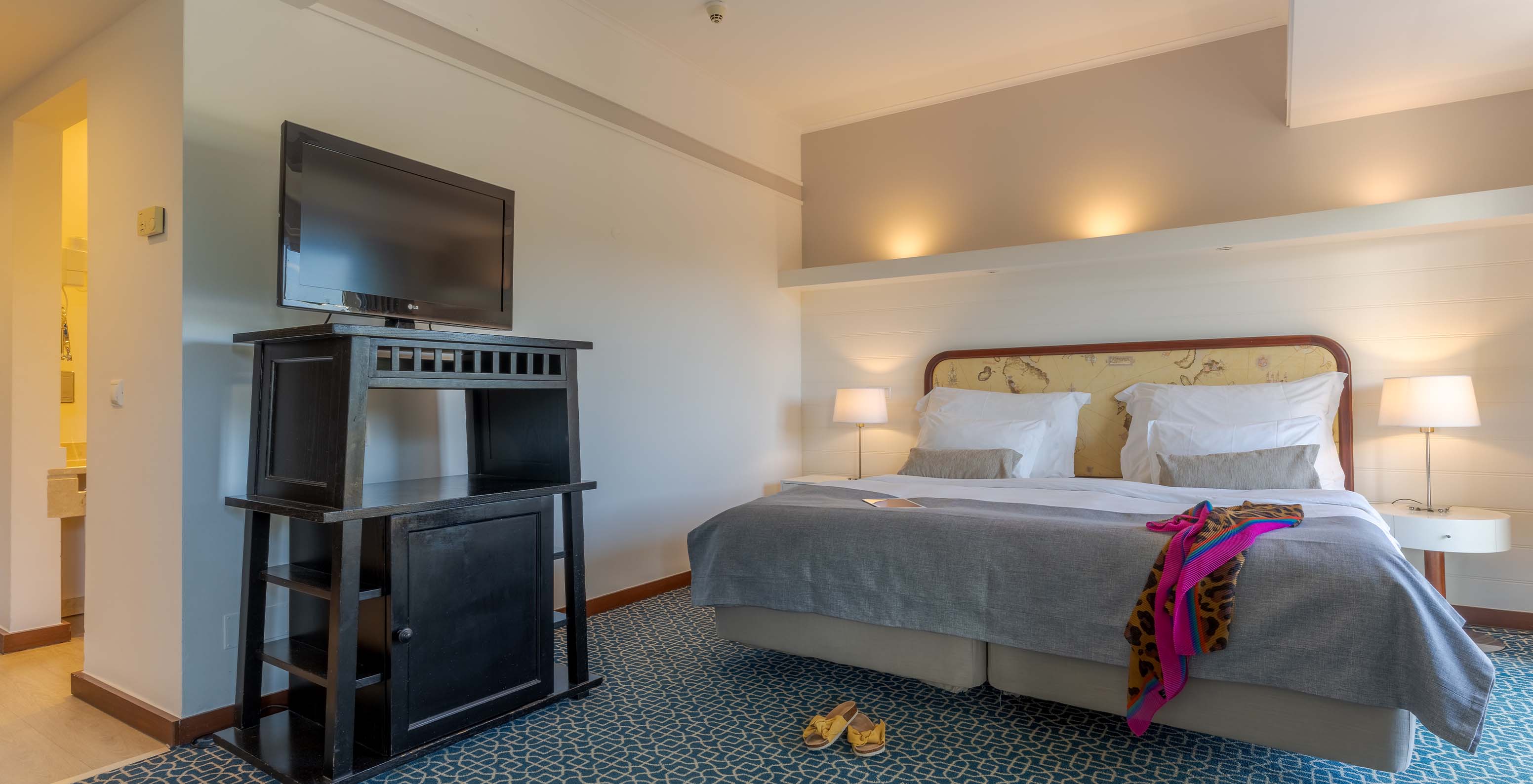 The Superior at Pestana Alvor Praia has two joined beds with a headboard, a black unit with TV, and a rug