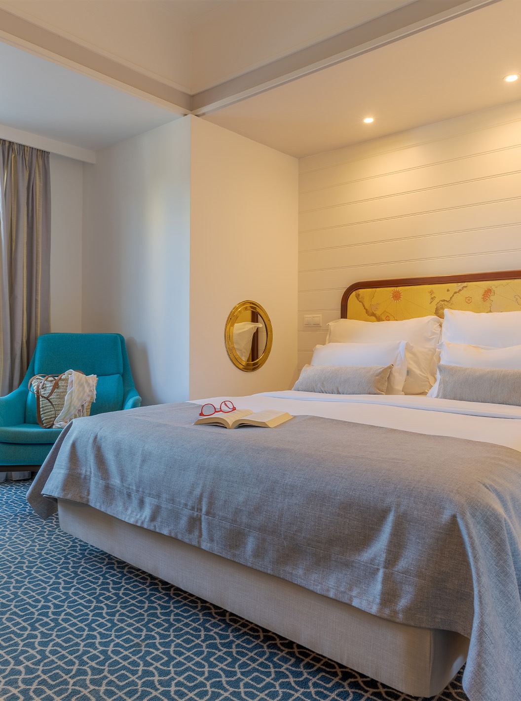 The Garden View Deluxe at Pestana Alvor Praia has a double bed, a blue armchair, and a window to the balcony