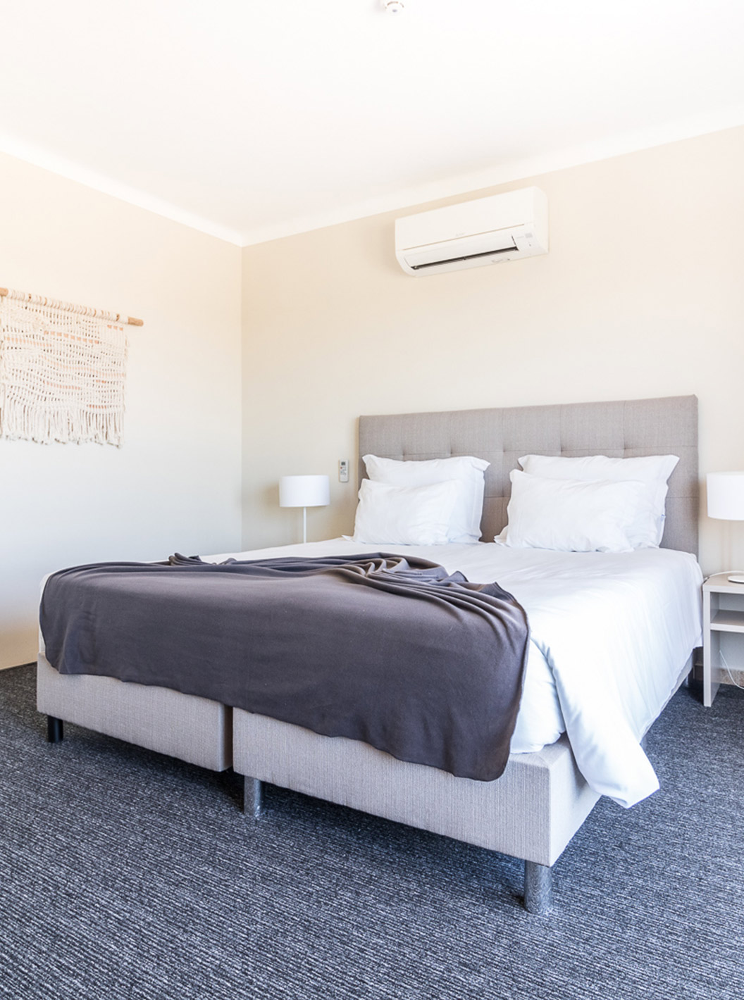 The two-bedroom apartment at Pestana Gramacho has a modern bedroom with bed, AC and minimalist decor