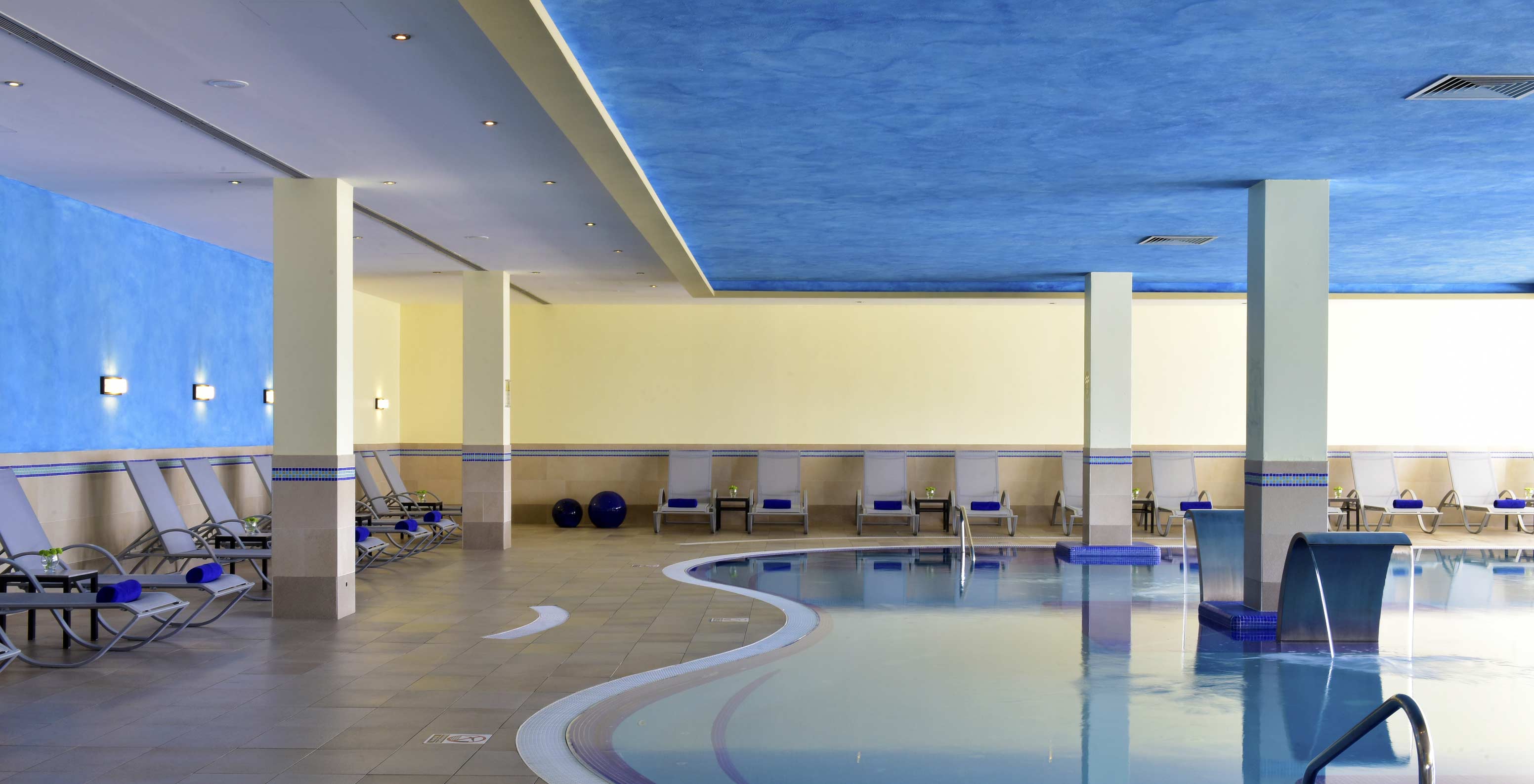 Indoor pool at Pestana Viking, blue and yellow walls, calm atmosphere, with several sun loungers