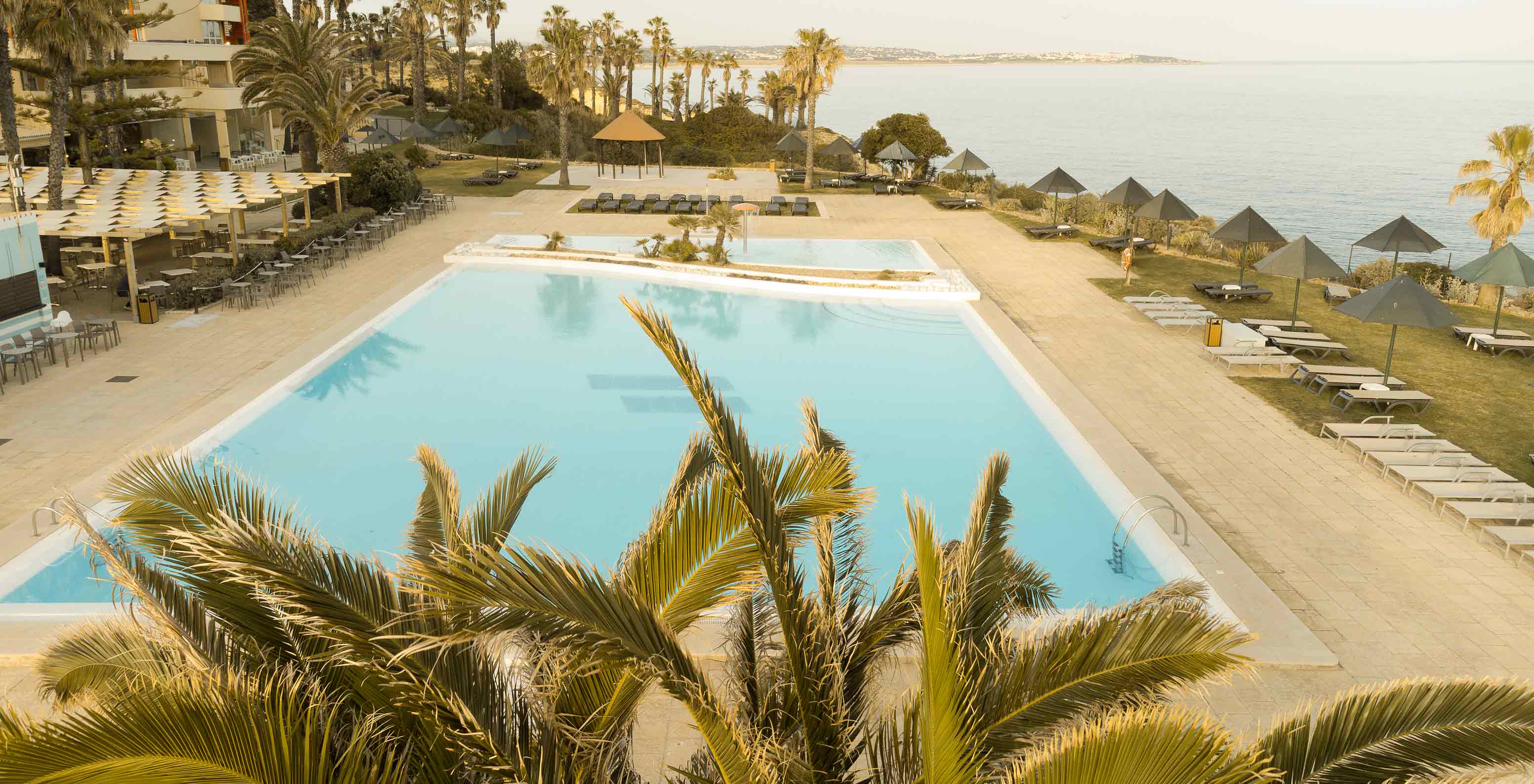 Outdoor pool at Pestana Viking, with palm trees, sun loungers and sea view
