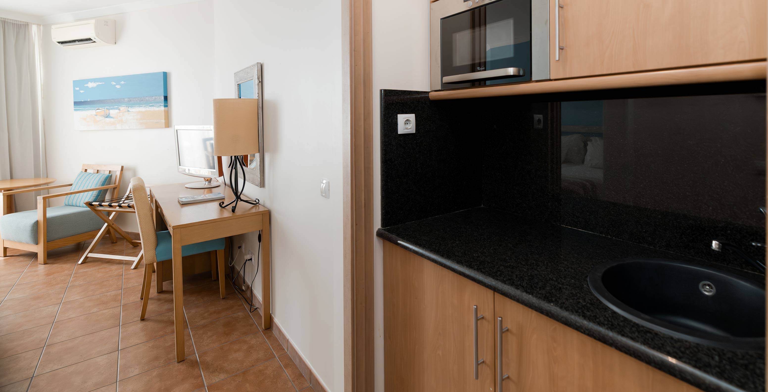 The Deluxe at Pestana Viking has a desk and a small kitchen with microwave and several cabinets