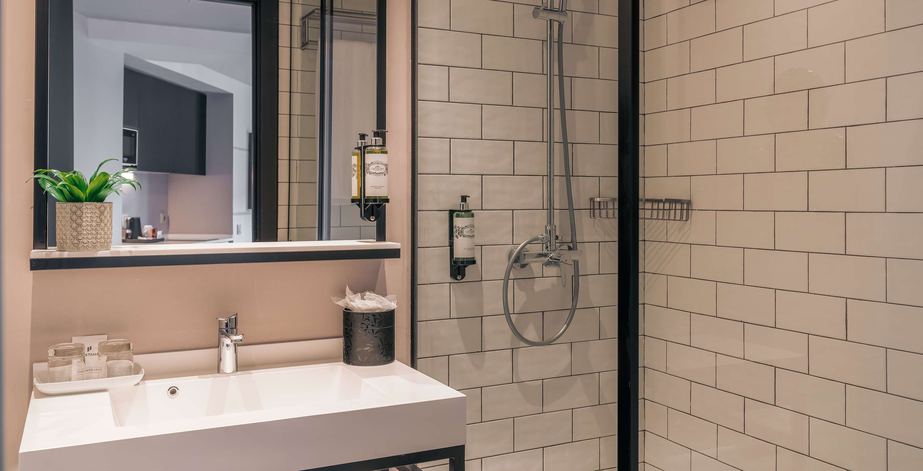 The Double Deluxe Studio at Pestana Lisboa Vintage has a shower with glass doors and black details, and a sink