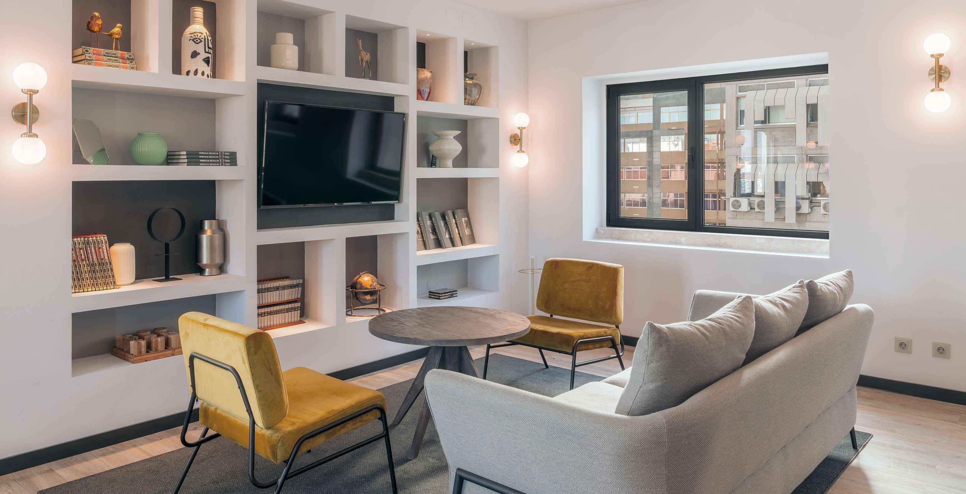 Lounge with sofas, chairs, tables, paintings, television, rugs and decor items with windows overlooking the city