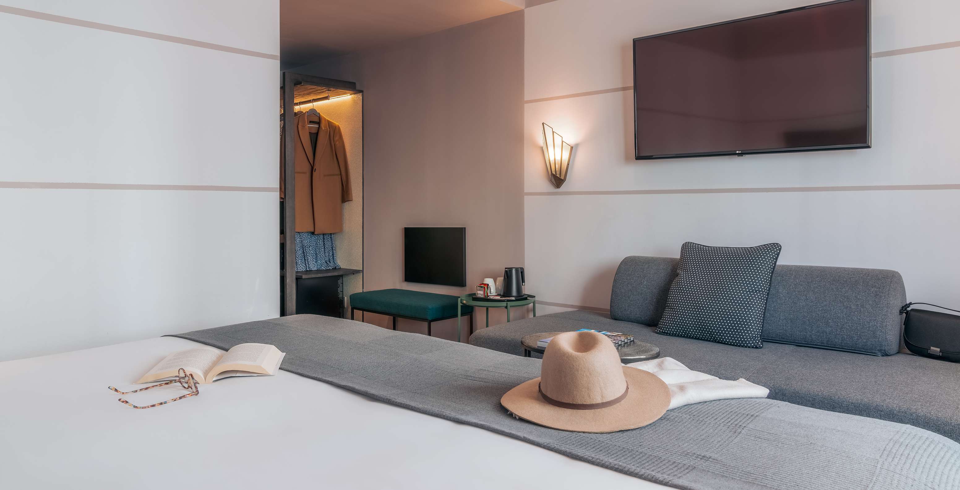 The Double Classic Room at Pestana Lisboa Vintage has a double bed with gray blanket, gray sofa and a TV