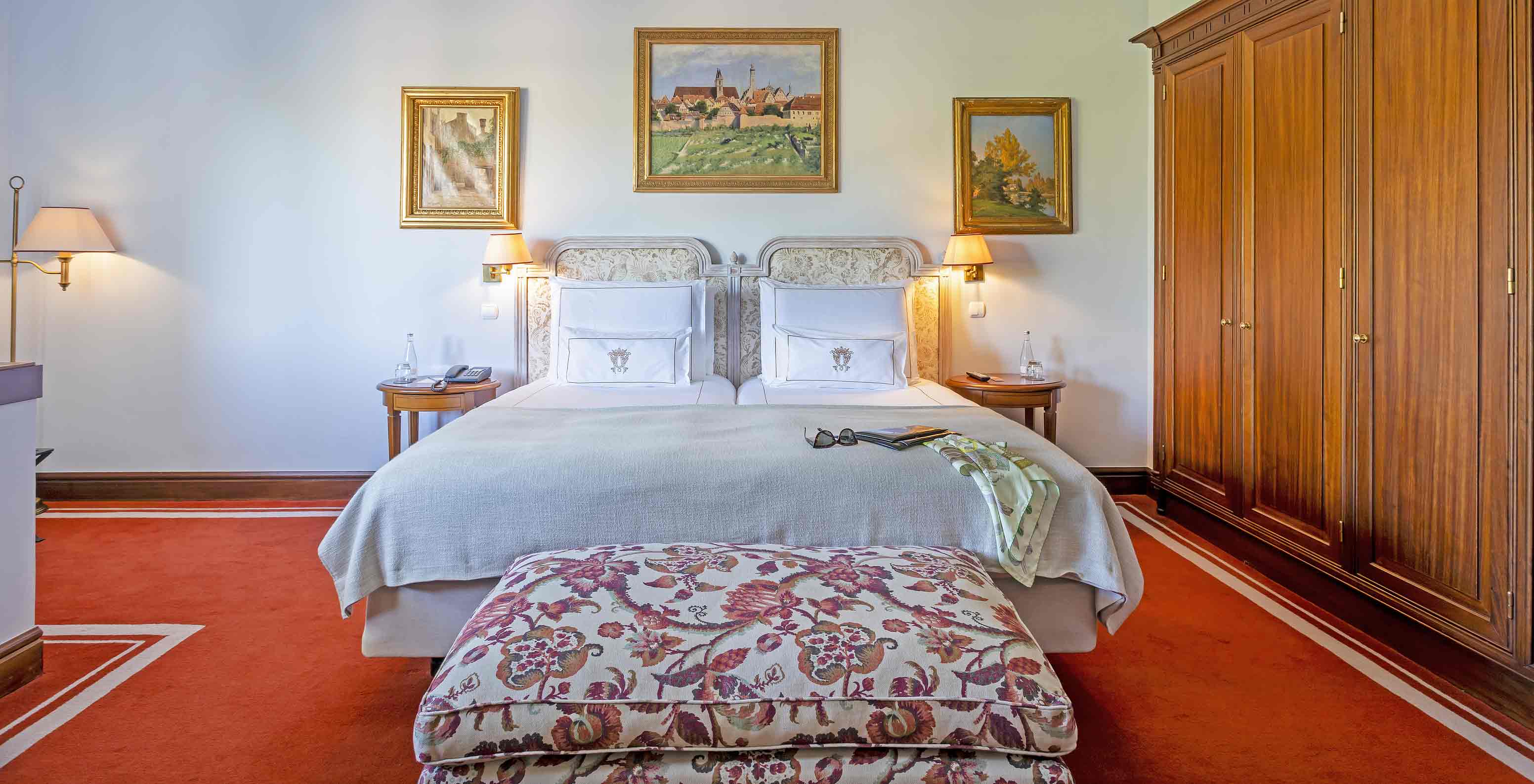 The Suite at Pestana Palace Lisboa has a double bed with a bench at the foot of the bed and a large wardrobe
