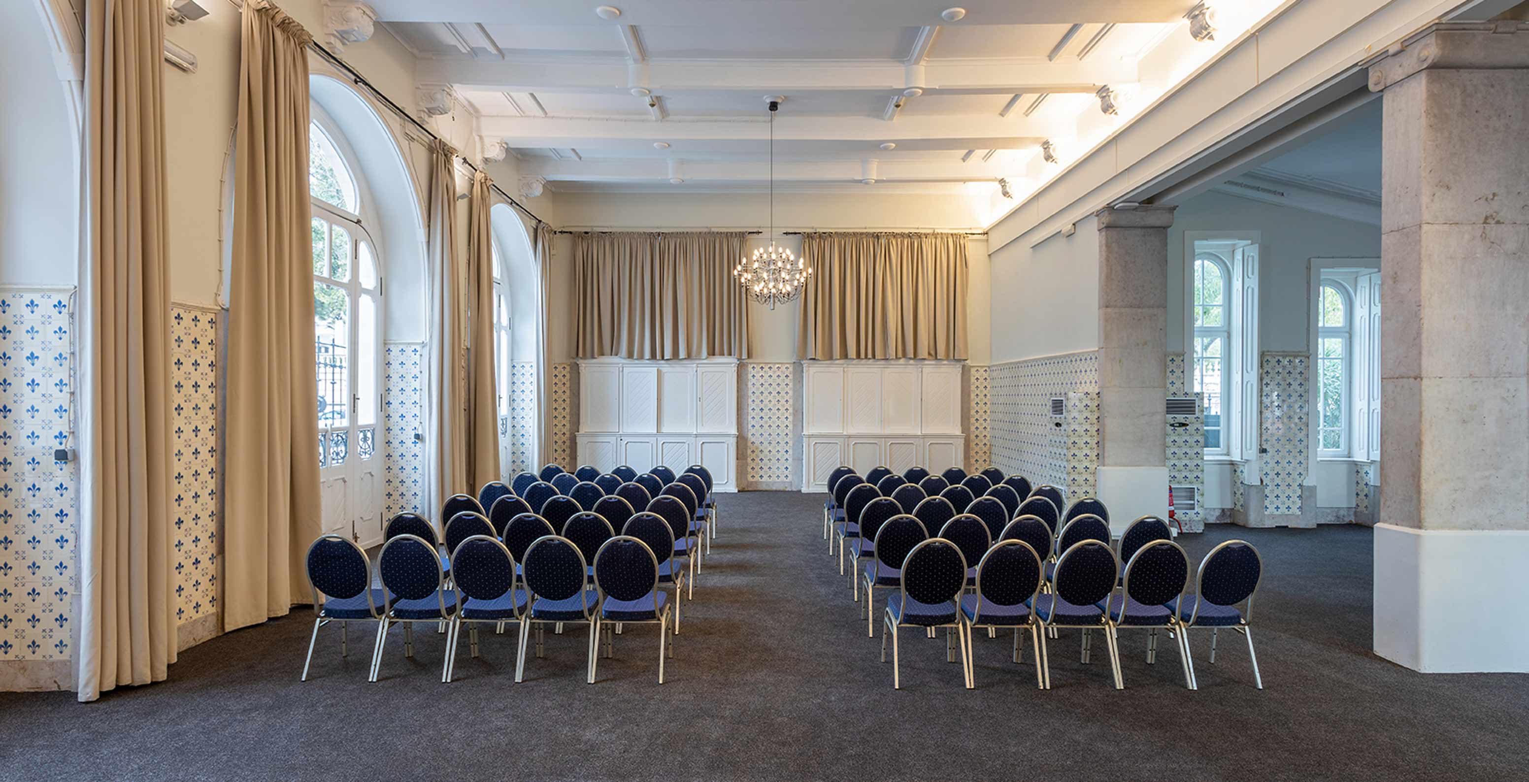 Pestana Palace Lisboa has a meeting and event room with blue chairs and windows with long curtains