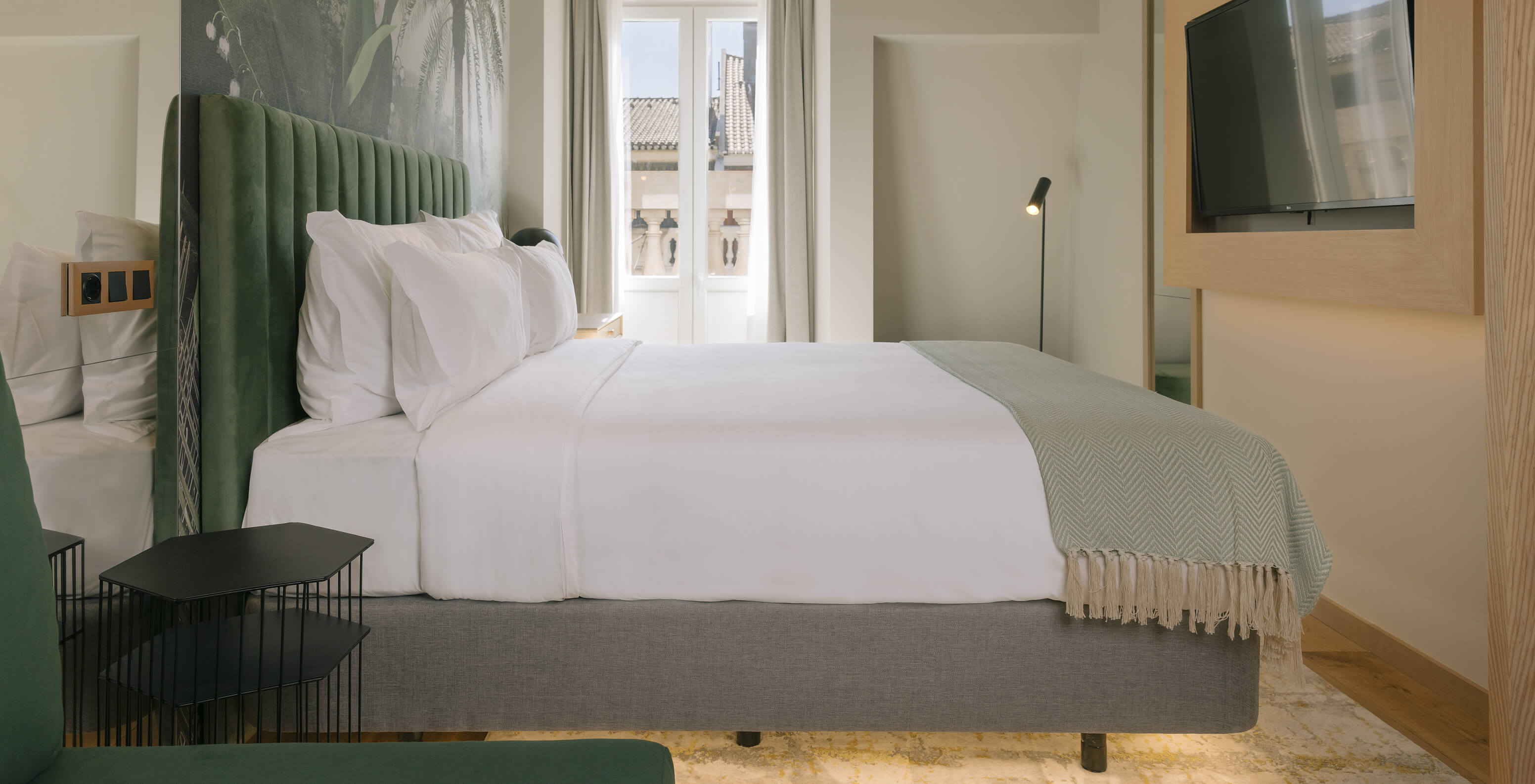 The Superior Plus room at the Pestana Rua Augusta Lisboa has a double bed, palm tree wallpaper and window