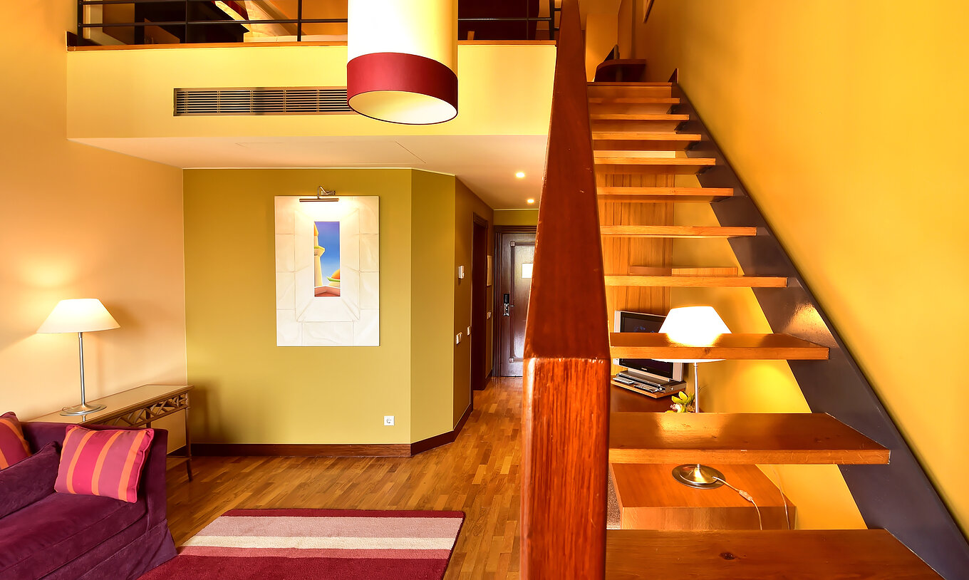 The Mezzanine Jacuzzi Suite of Pestana Sintra Golf has a sofa, stairs to the mezzanine, a picture, and a lamp