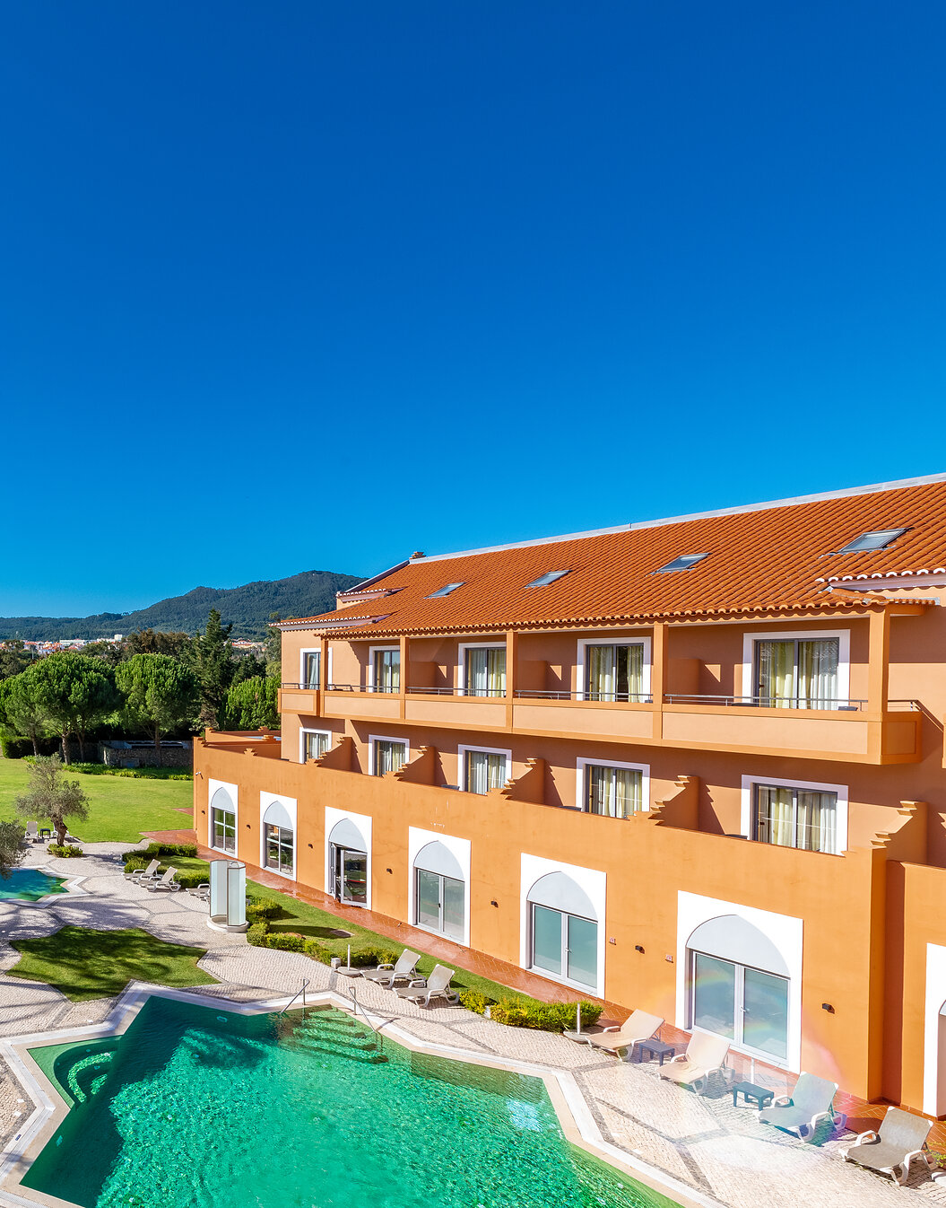 View of Pestana Sintra Golf, a 4-star hotel in Sintra, with an outdoor pool, garden with trees, and a golf course