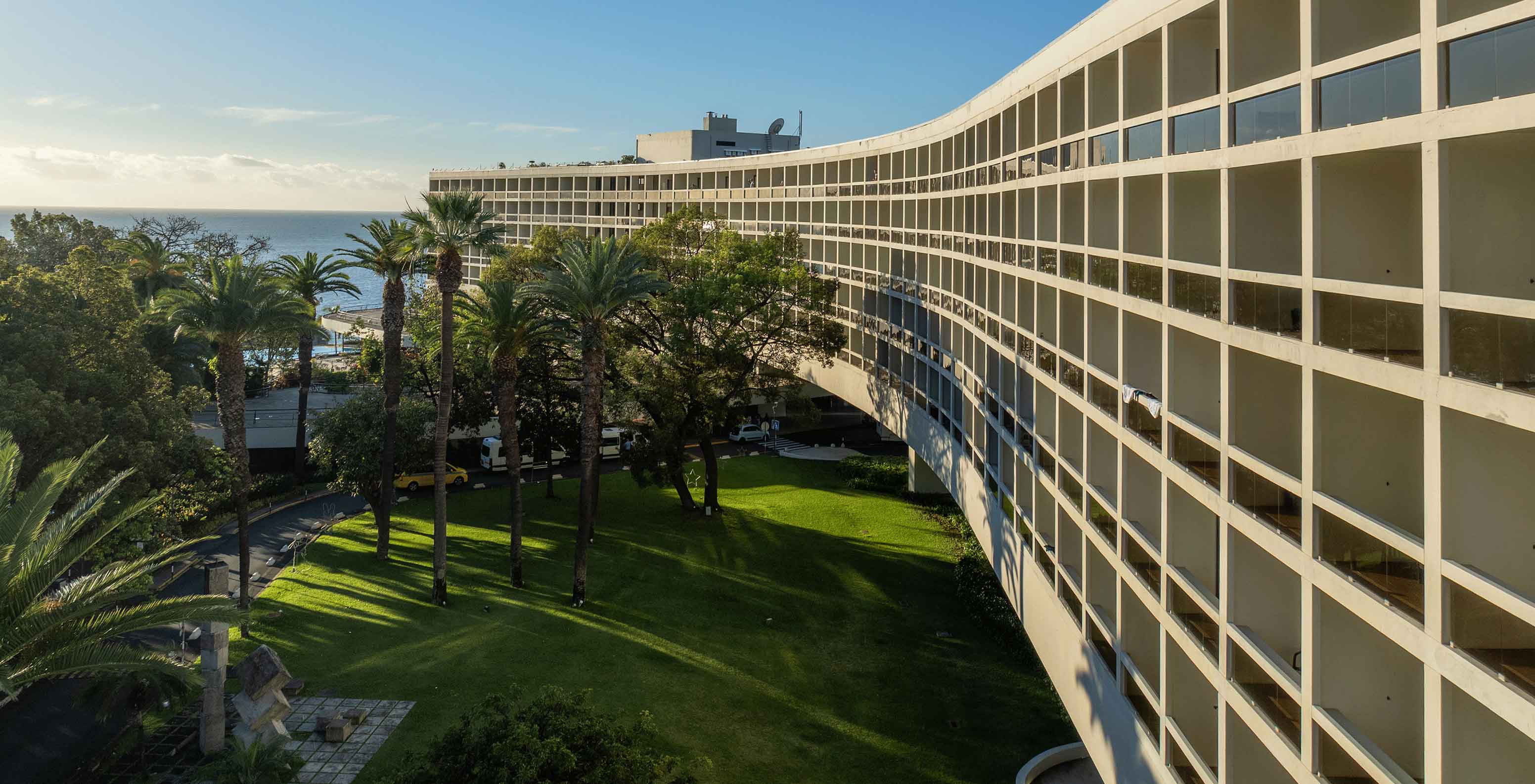 Exterior view of the Pestana Casino Park, with swimming pool, sun loungers, surrounded by flowers and palm trees