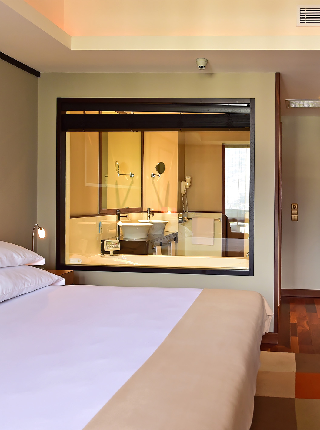 The Presidential Suite at Pestana Casino Park has a double bed with glass to the bathroom and decorative wallpaper