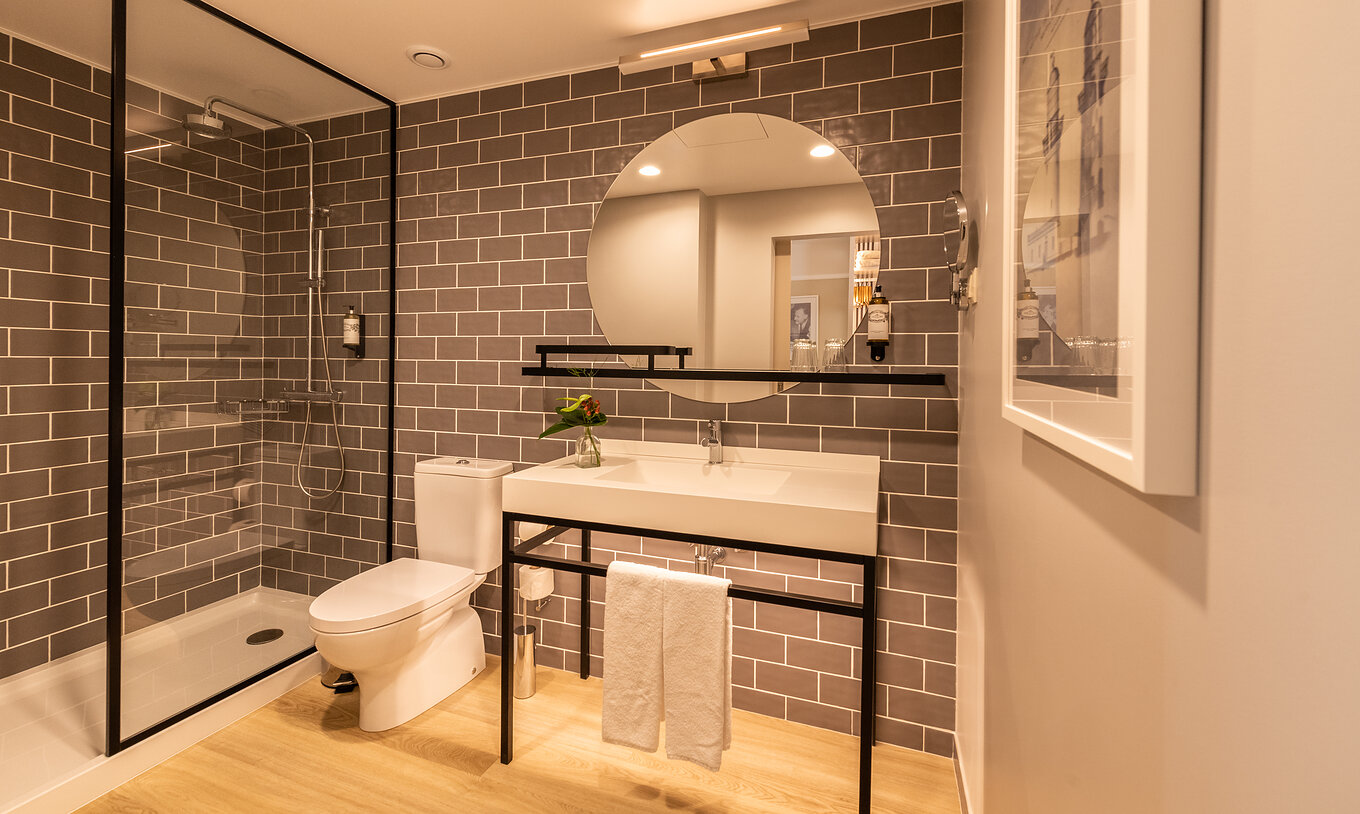 The Superior Family room at Pestana Fisherman Village features a bathroom with a shower, toilet, and a round mirror