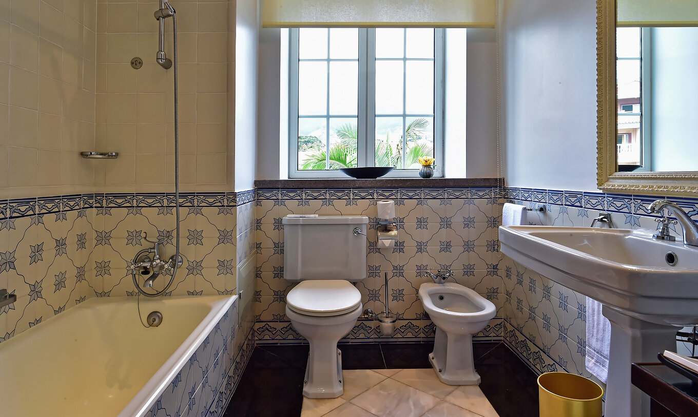 The Miramar Suite at Pestana Miramar has a bathroom with blue flower tiles, bathtub, toilet, bidet and sink