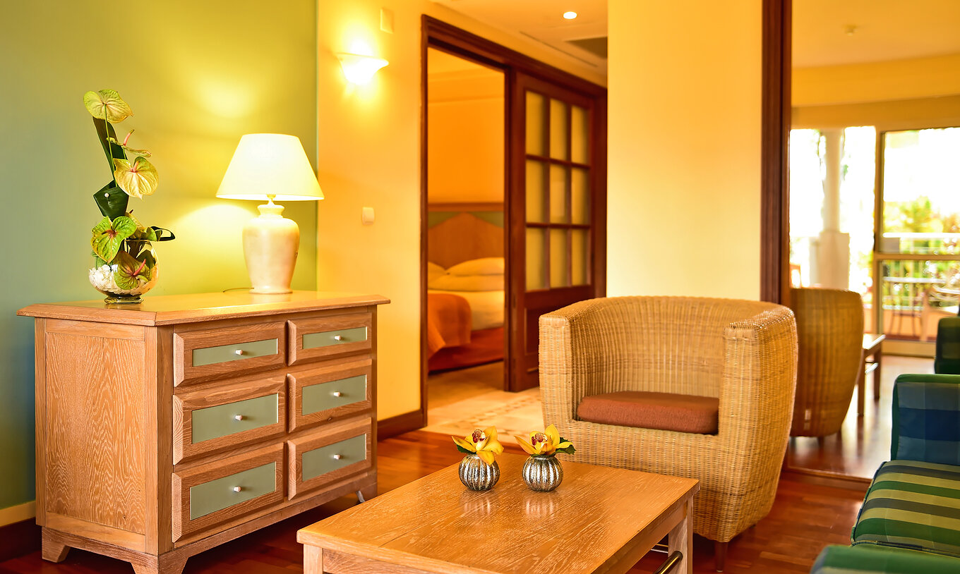 The Family Superior Room at Pestana Miramar has a chest with drawers, a wicker armchair and a double bed at the back