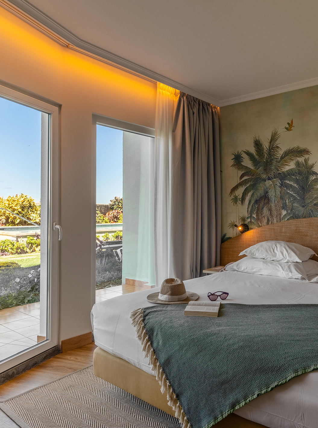 The Pestana Ocean Bay All Inclusive Junior Suite Sea View has a double bed with a green bedspread and wallpaper