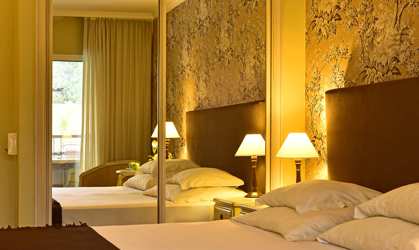 The Suite with Jacuzzi at Pestana Village has a double bed with headboard and brown bedspread, and wardrobe with mirror