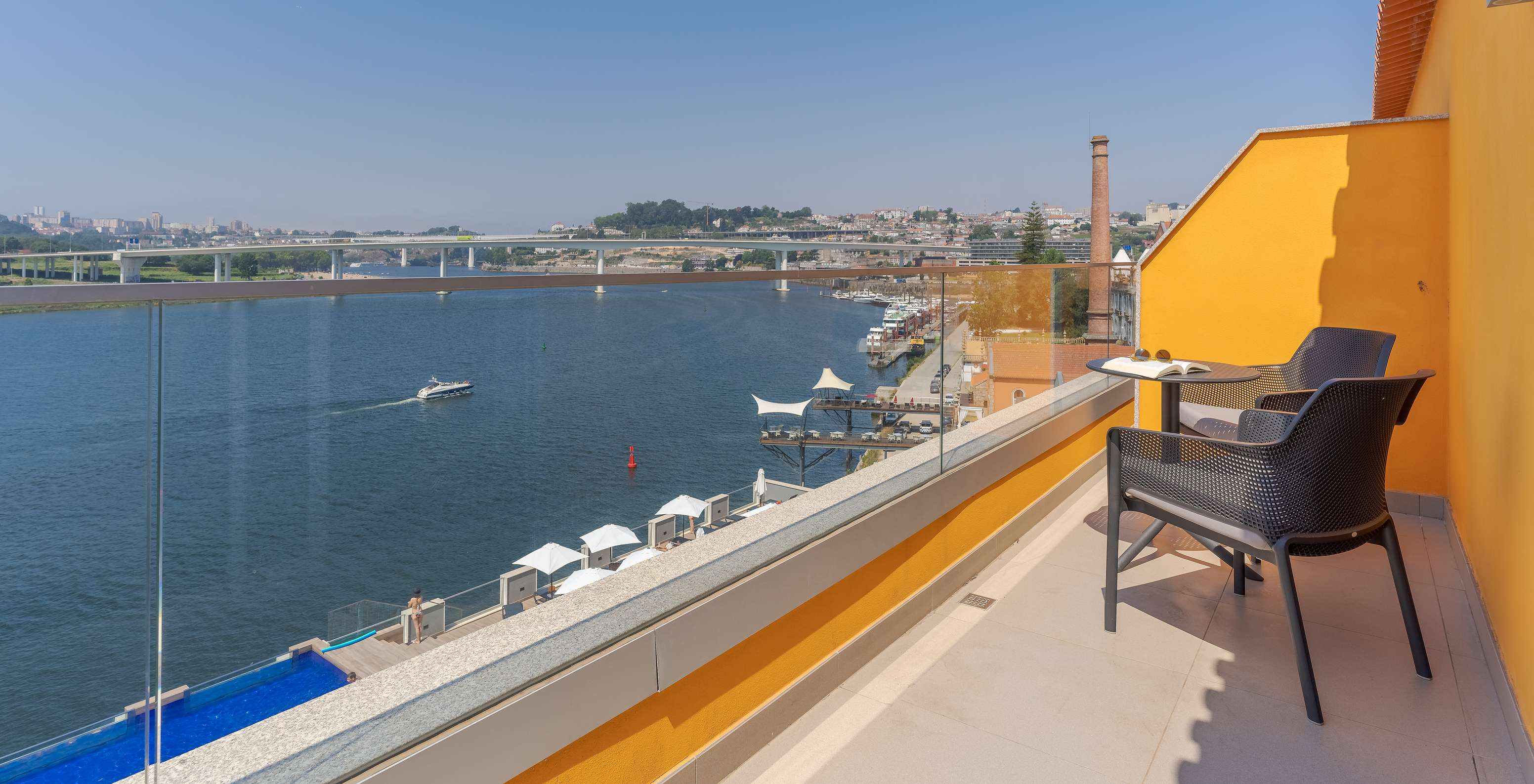 The Suite at Pestana Douro Riverside has a balcony with a view of the Douro River, with table, chairs, and loungers