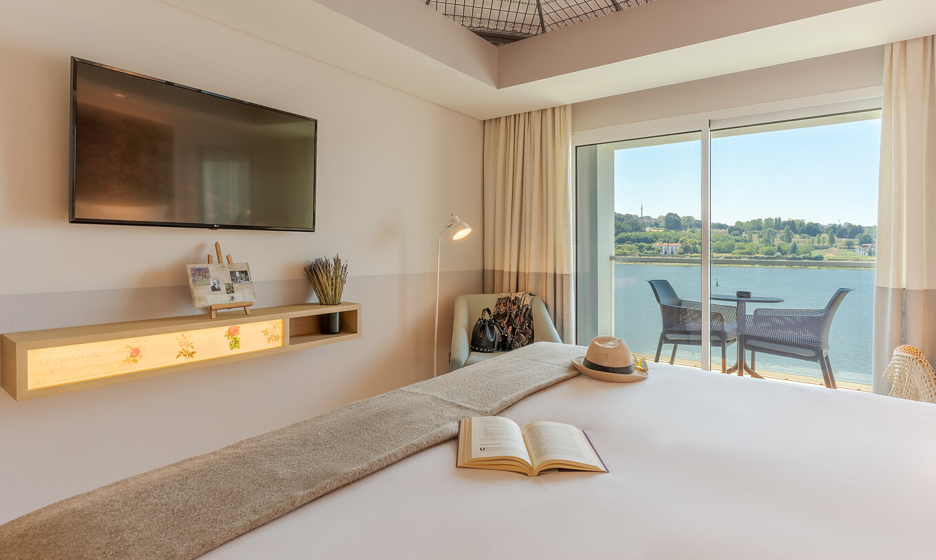 The Deluxe River View at Pestana Douro Riverside includes a double bed, television, and an armchair