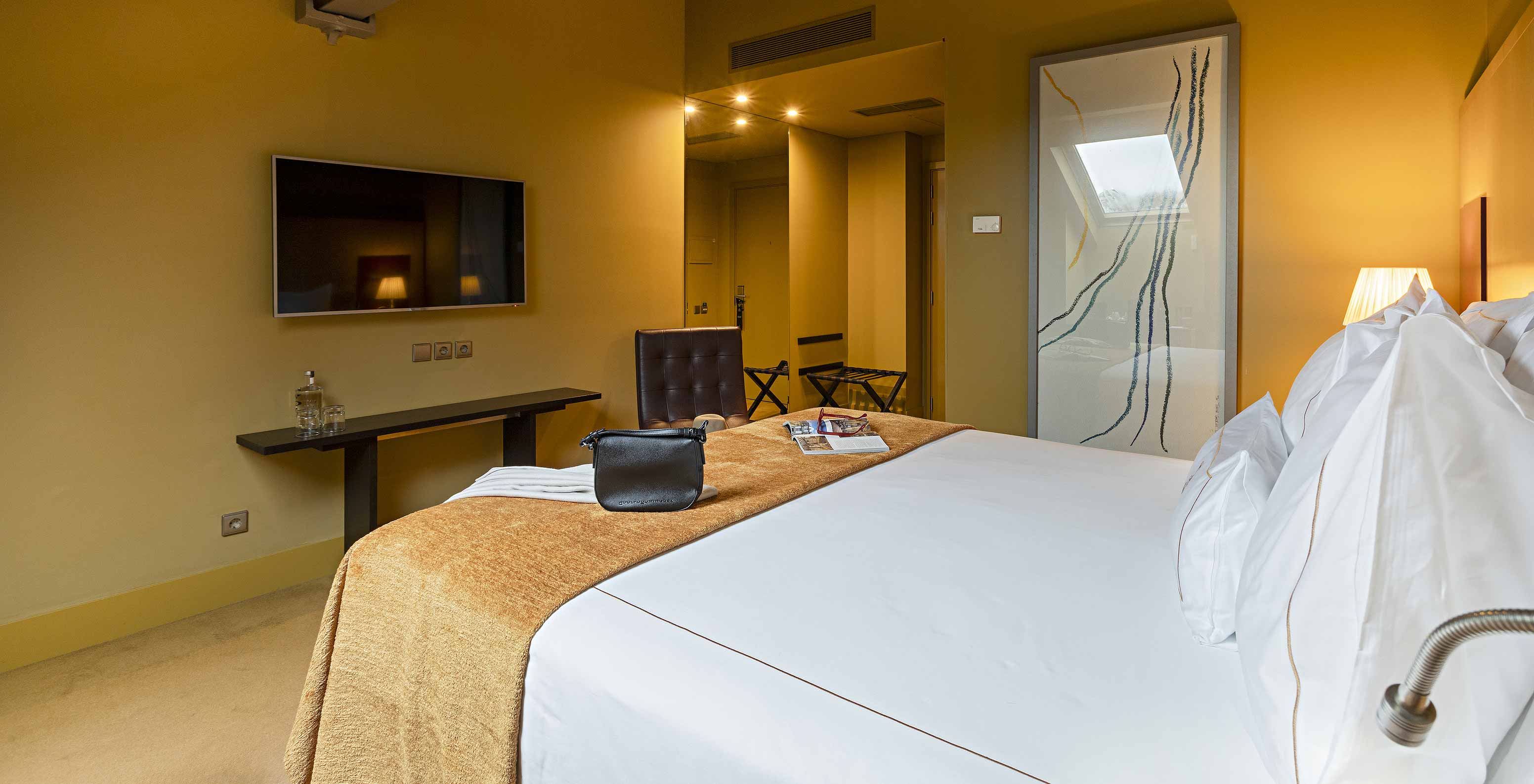Pestana Palácio do Freixo’s Classic Attic has a double bed, TV in front, and a table with water