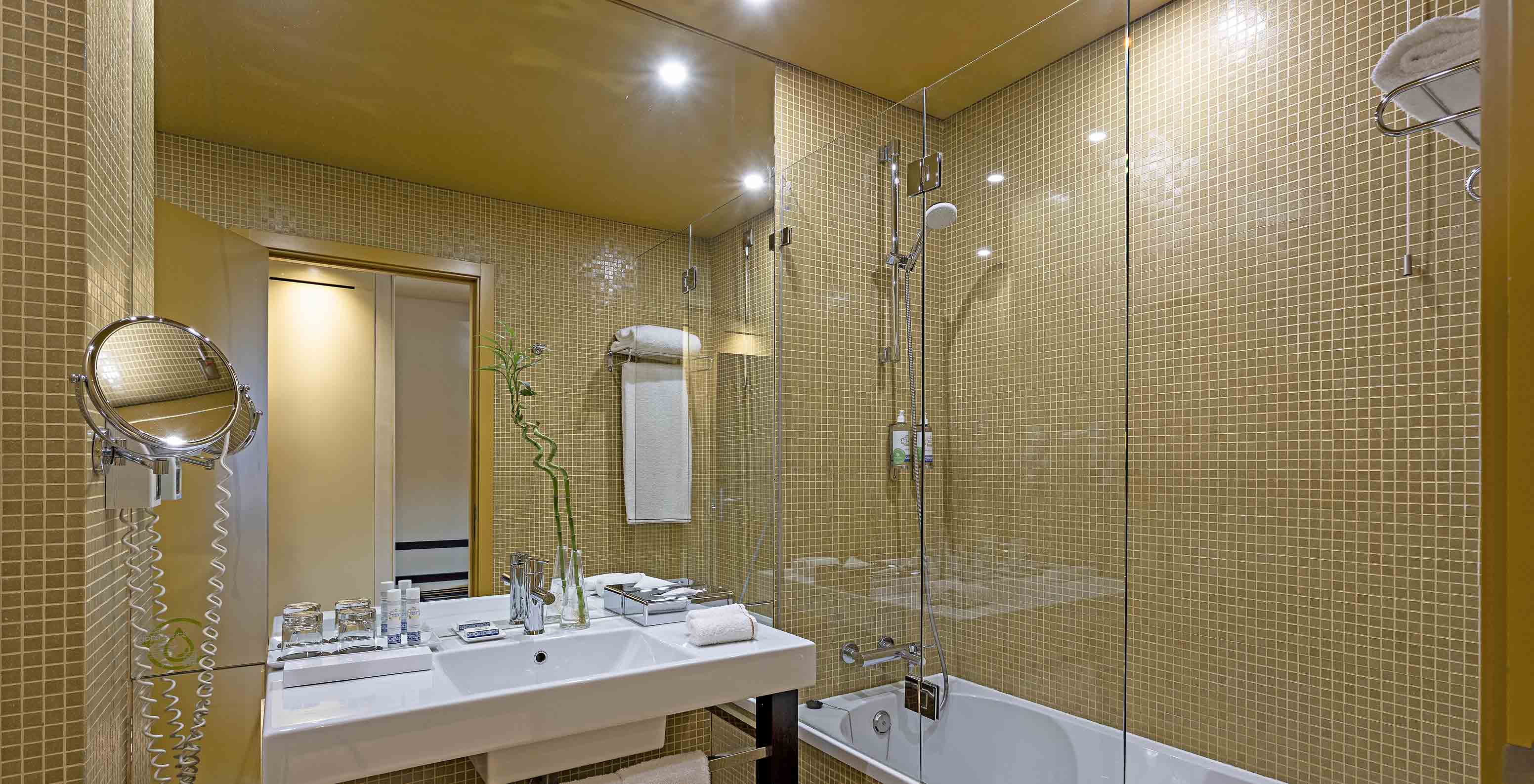 Pestana Palácio do Freixo’s Superior room has a bathroom with yellow tiles, washbasin, and bathtub