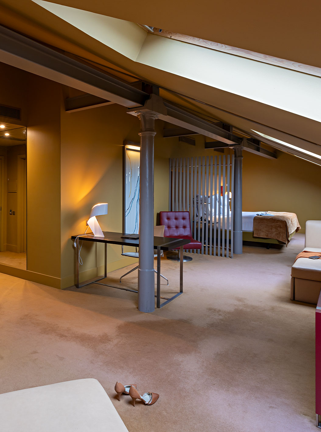 Pestana Palácio do Freixo’s Loft Attic has a beige leather sofa, a desk and a red cabinet