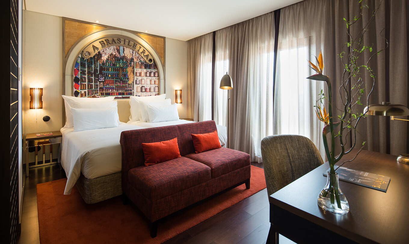 The Deluxe Superior Grand View do Pestana Porto - A Brasileira has a double bed with a sofa at the back and a desk